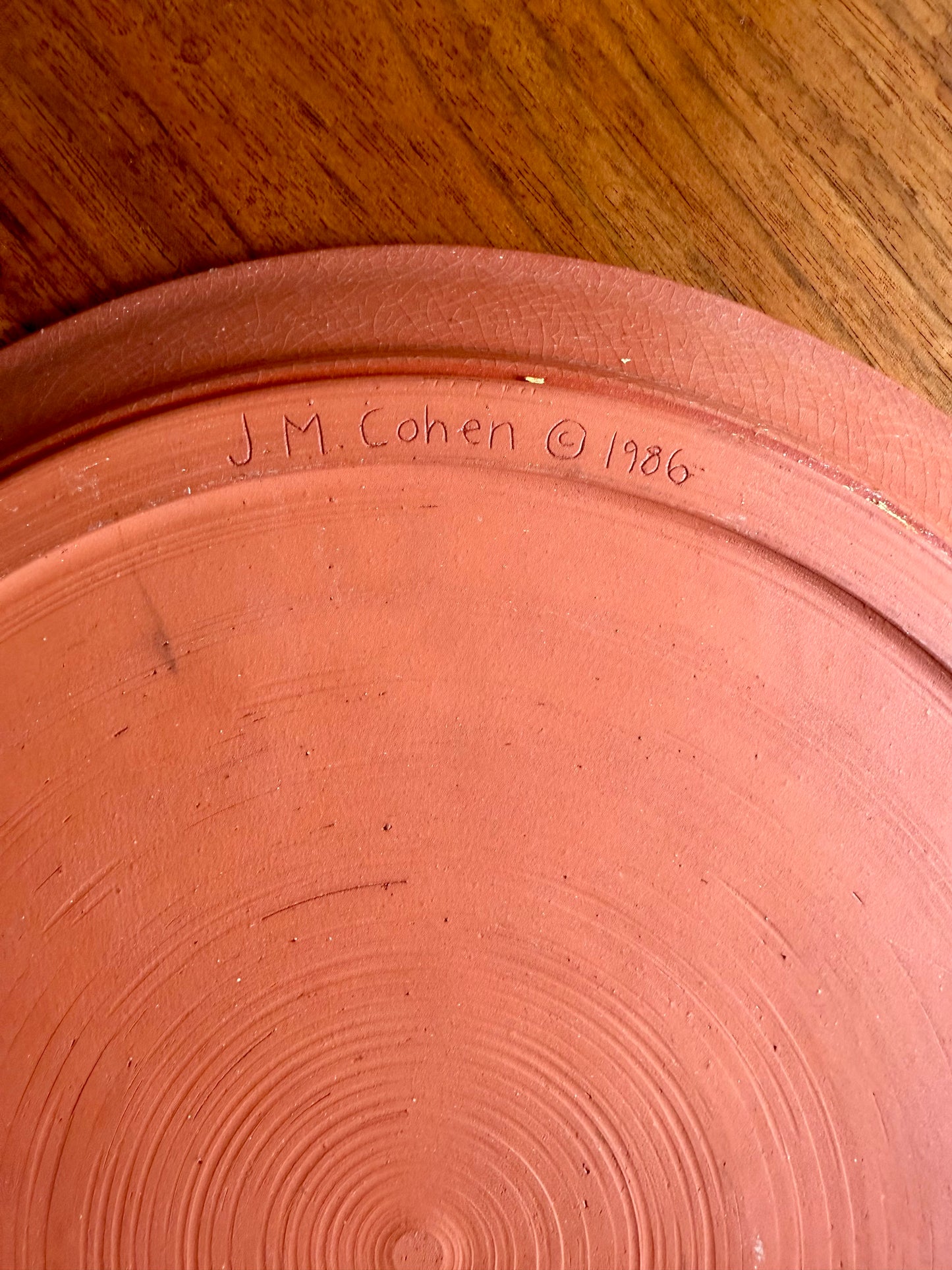Terracotta pot with 'J. M. Cohen 1986' inscription on a wooden surface