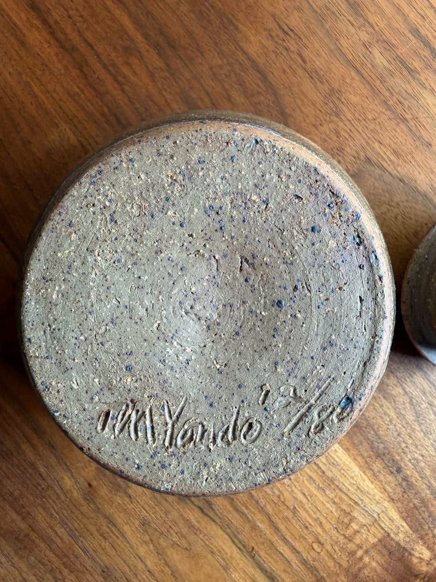 Round concrete coaster with 'Vander' branding on a wooden surface