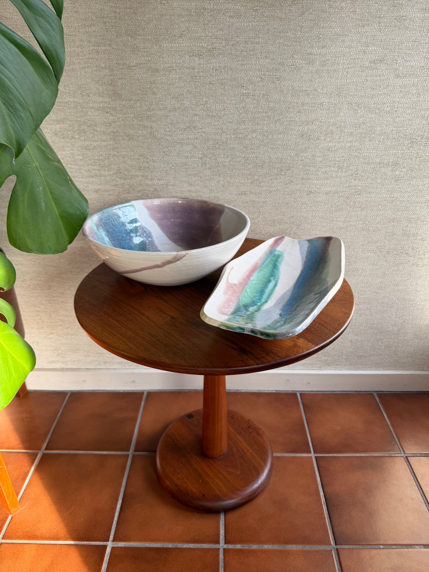 Small wooden table with two ceramic bowls on a tiled floor against a textured wall.