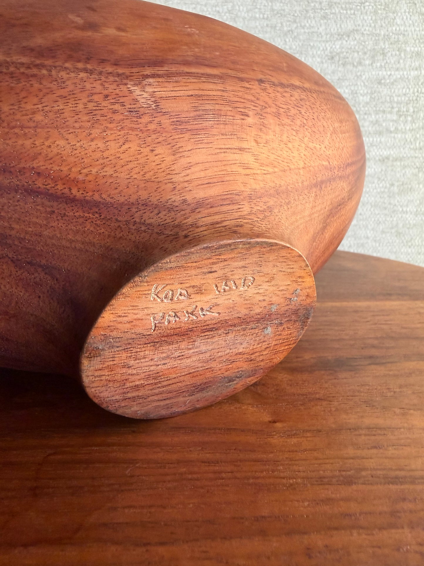 Close-up of a wooden product with 'Pakk' branding on a textured background