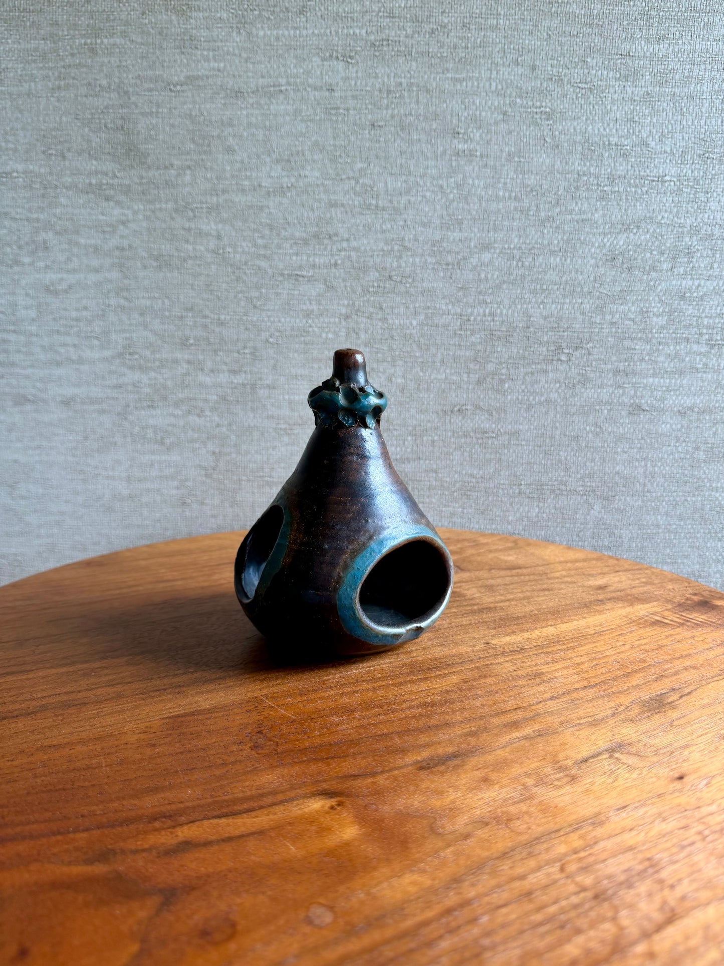 Small ceramic vase on a wooden surface with a gray background