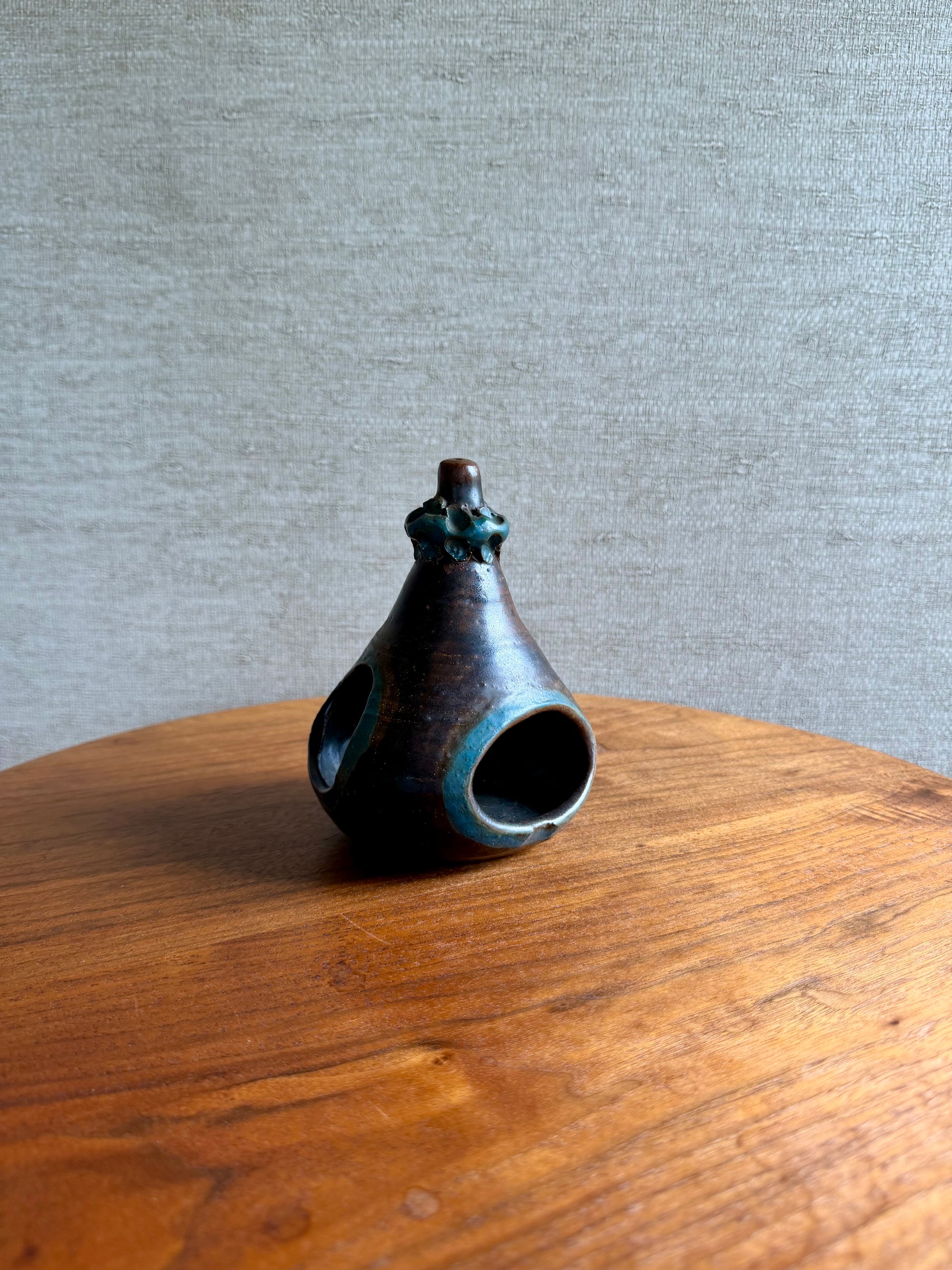 Small ceramic vase on a wooden surface with a gray background