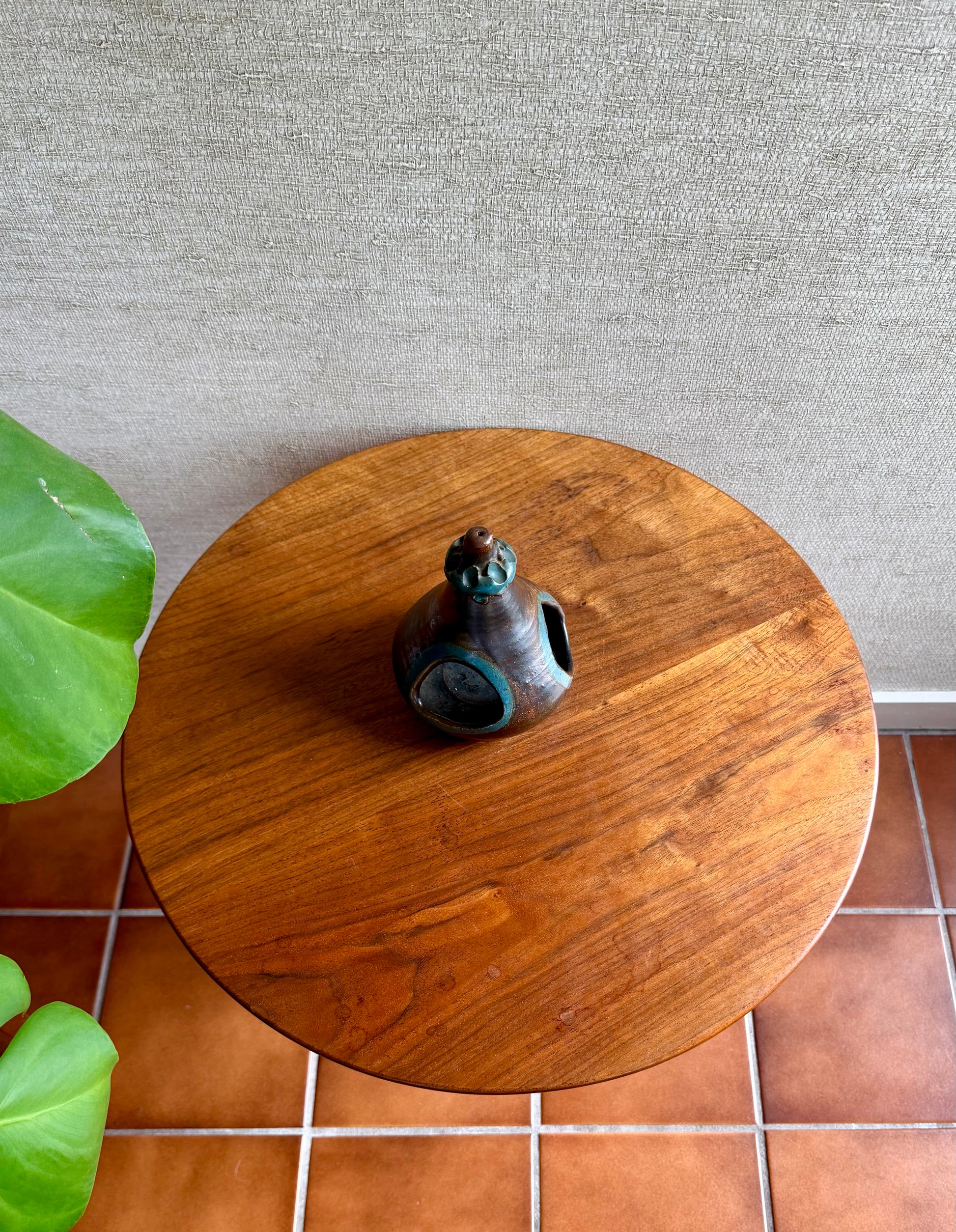 Wooden side table with a decorative object on a tiled floor