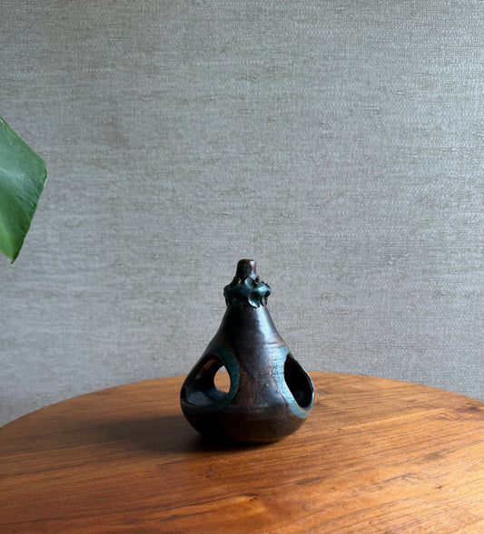 Black ceramic vase on a wooden surface with a gray textured wall background