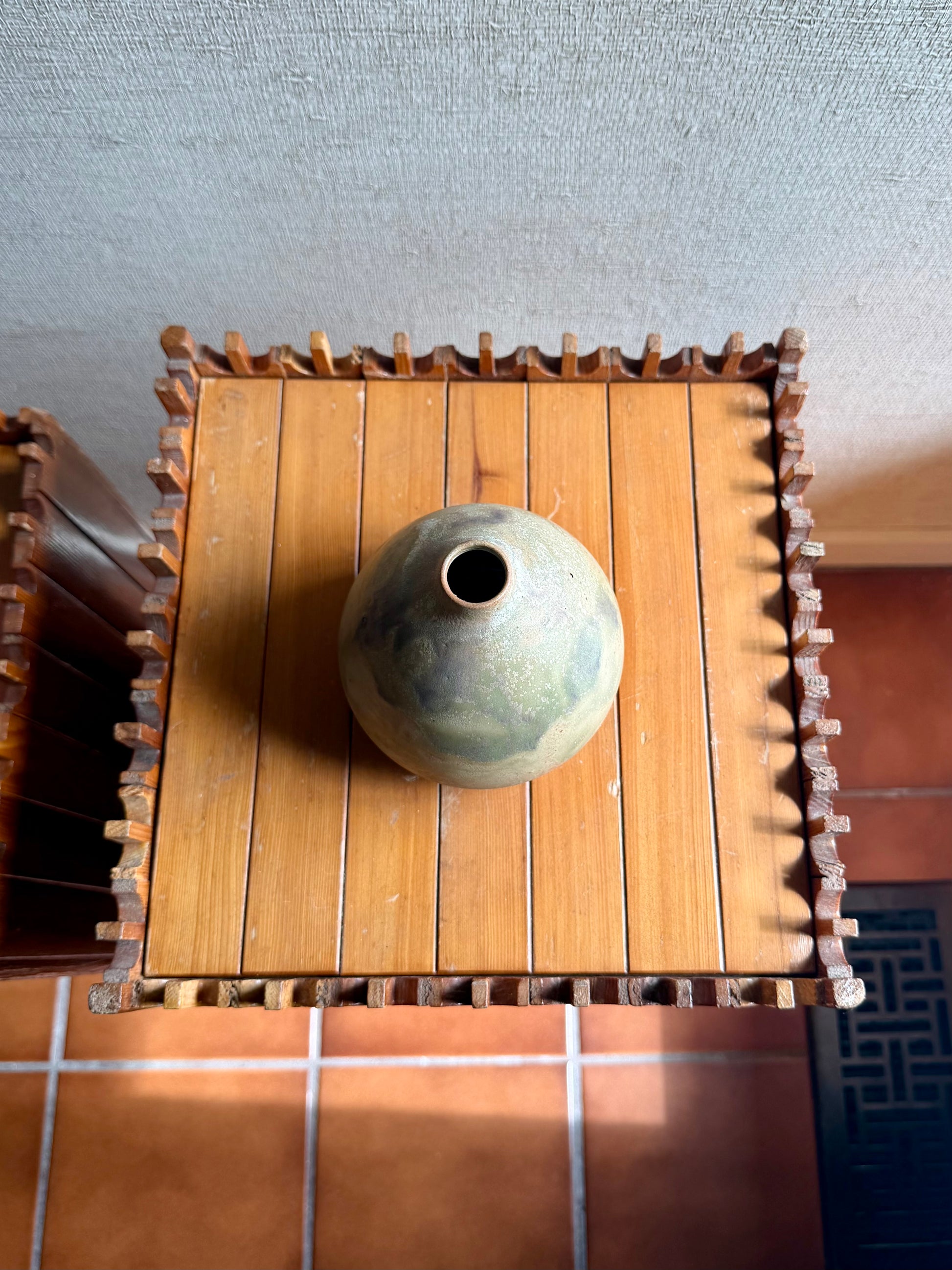 Small round object on a wooden stand with a textured wall background