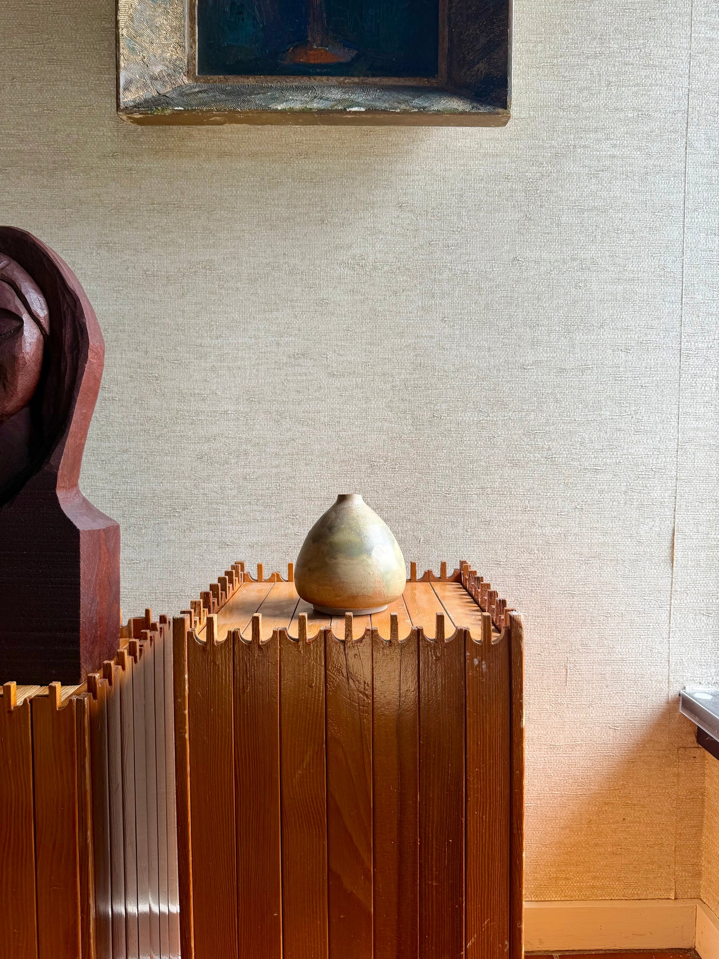 Decorative vase on a wooden cabinet with a textured wall in the background