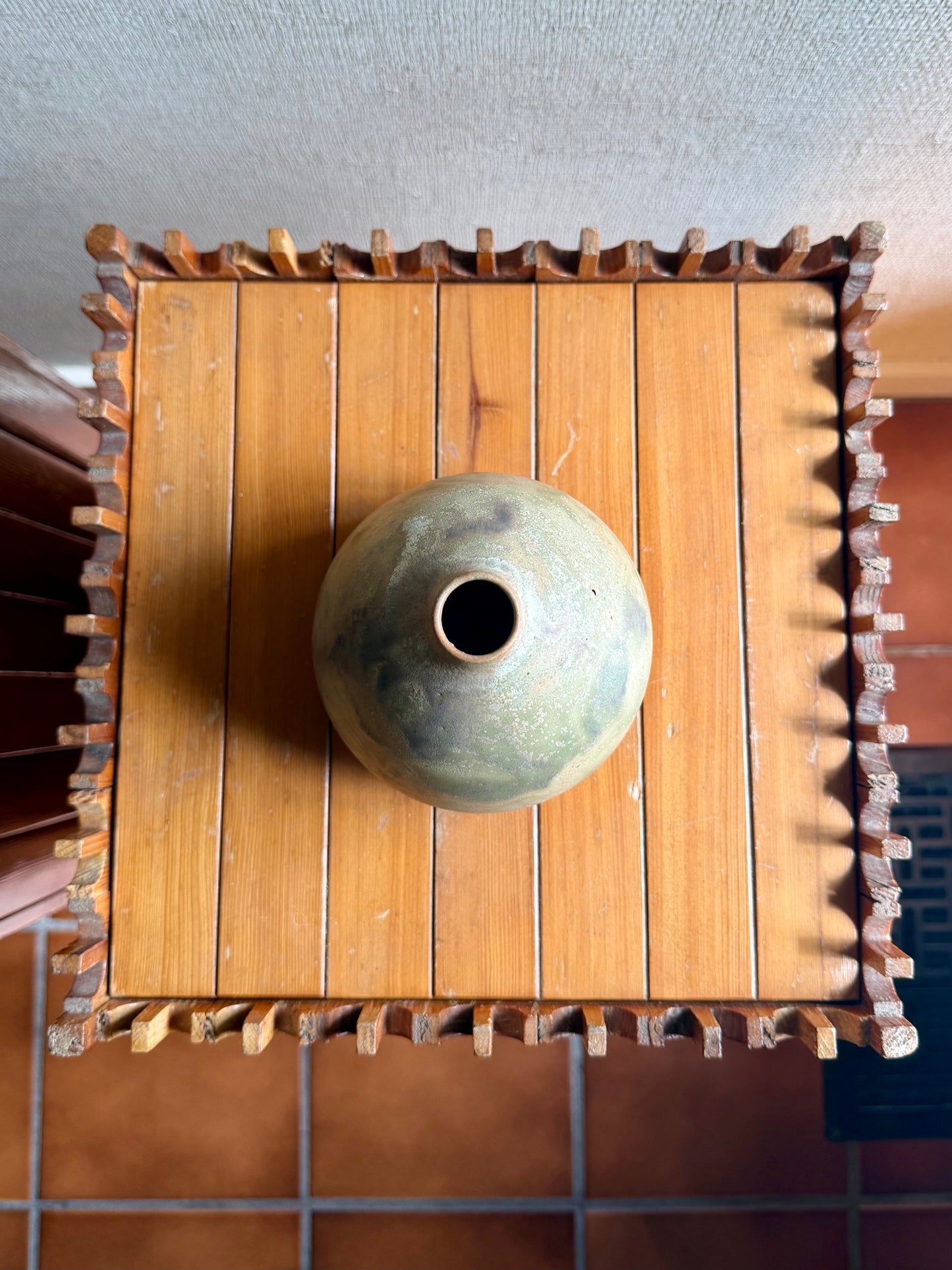 Wooden box with a ceramic vase on top against a neutral background