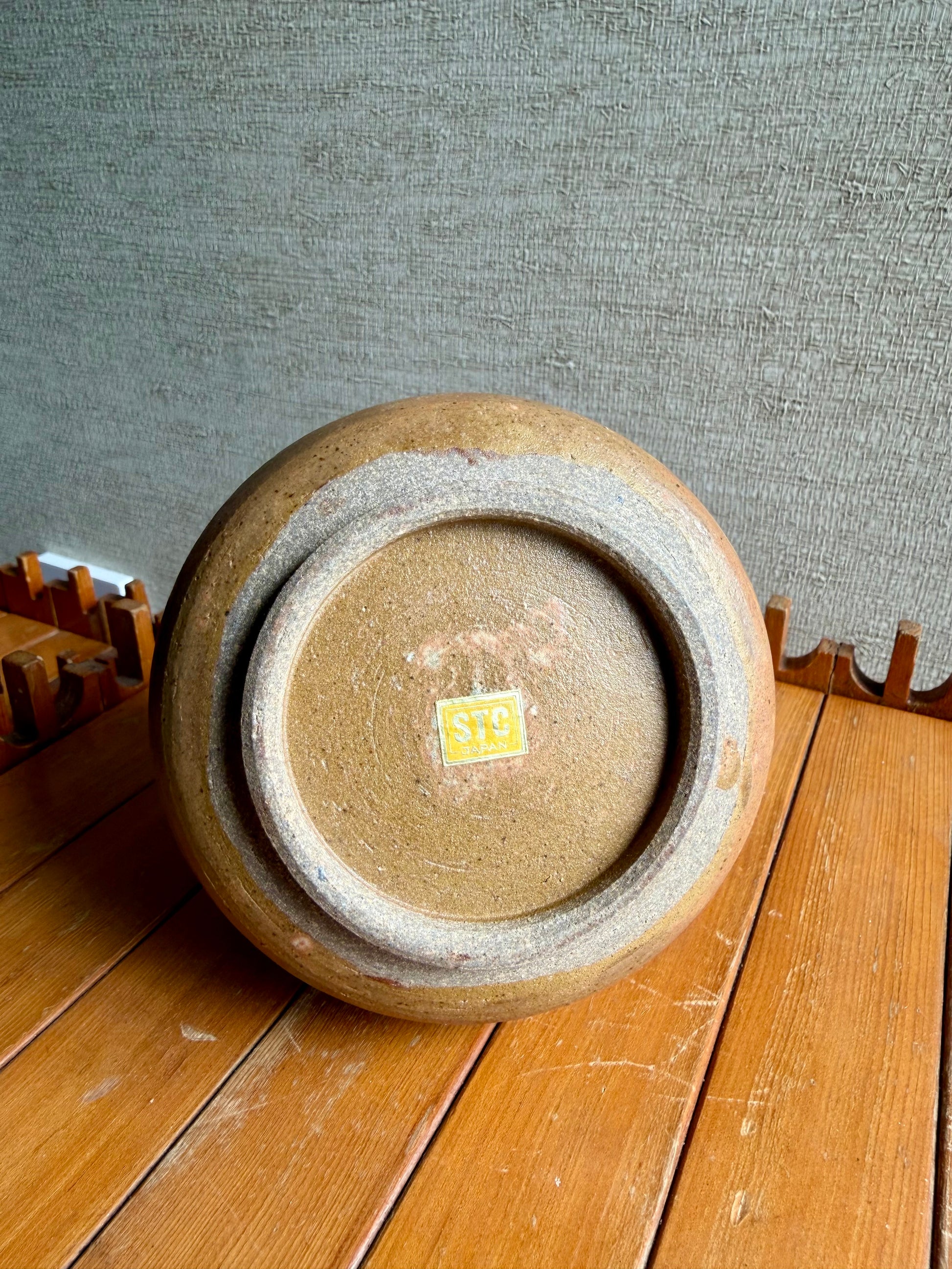 Ceramic pot on a wooden surface with a textured gray background