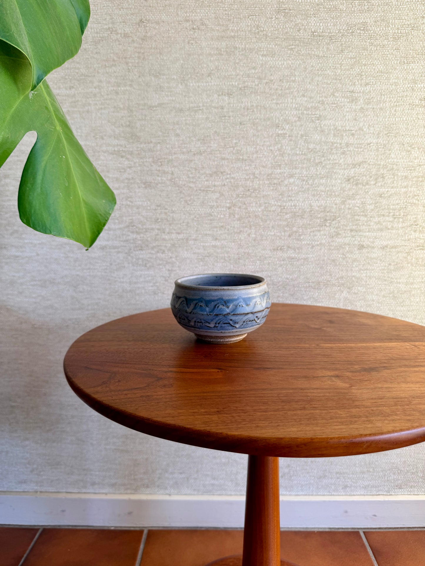 Small ceramic bowl on a wooden table with a textured wall background