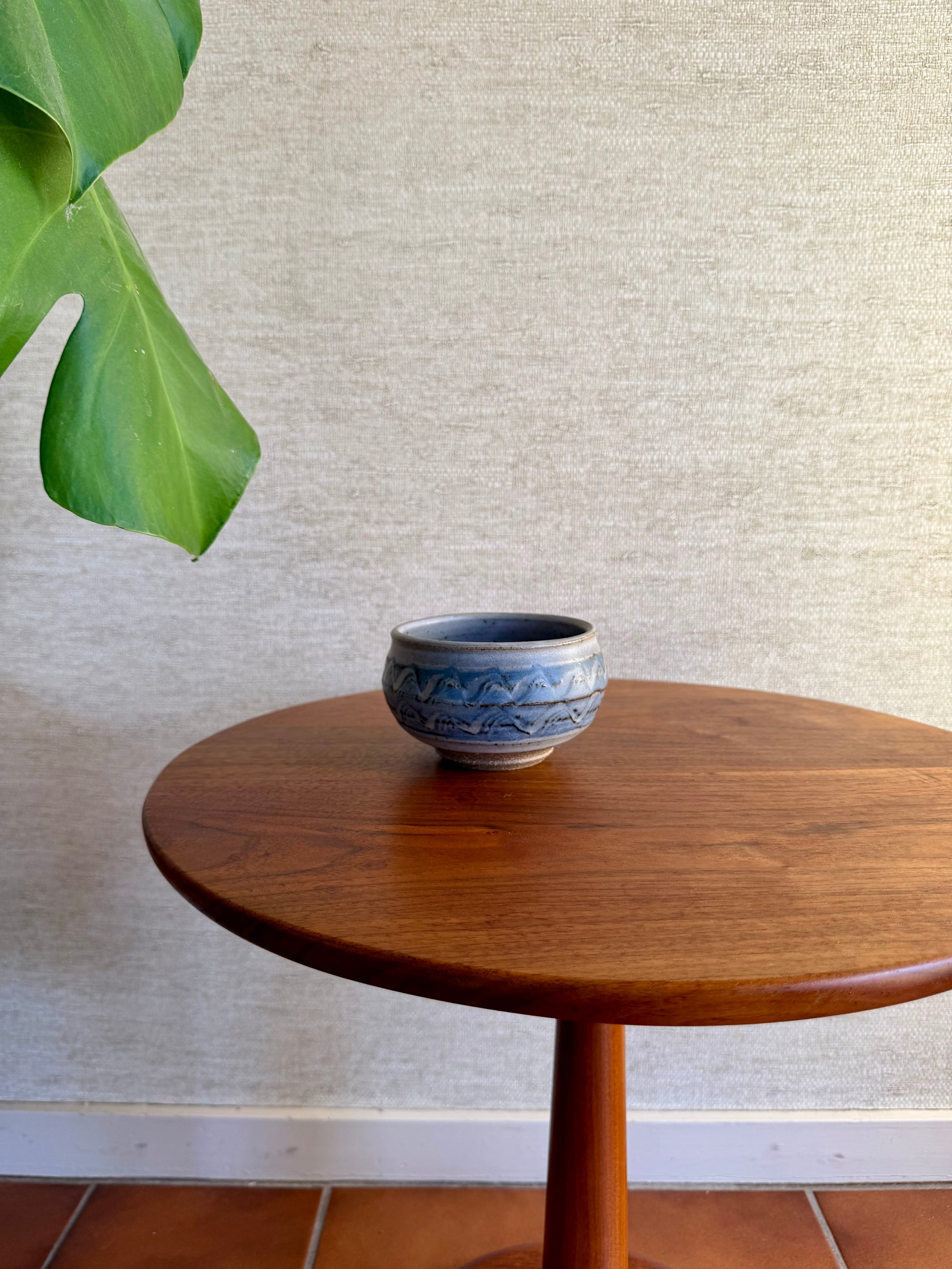 Small ceramic bowl on a wooden table with a textured wall background