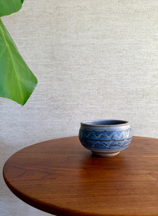 Blue ceramic bowl on a wooden table with a light gray textured wall in the background