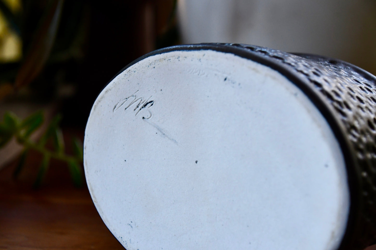 Close-up of a ceramic vase with a textured surface and white base