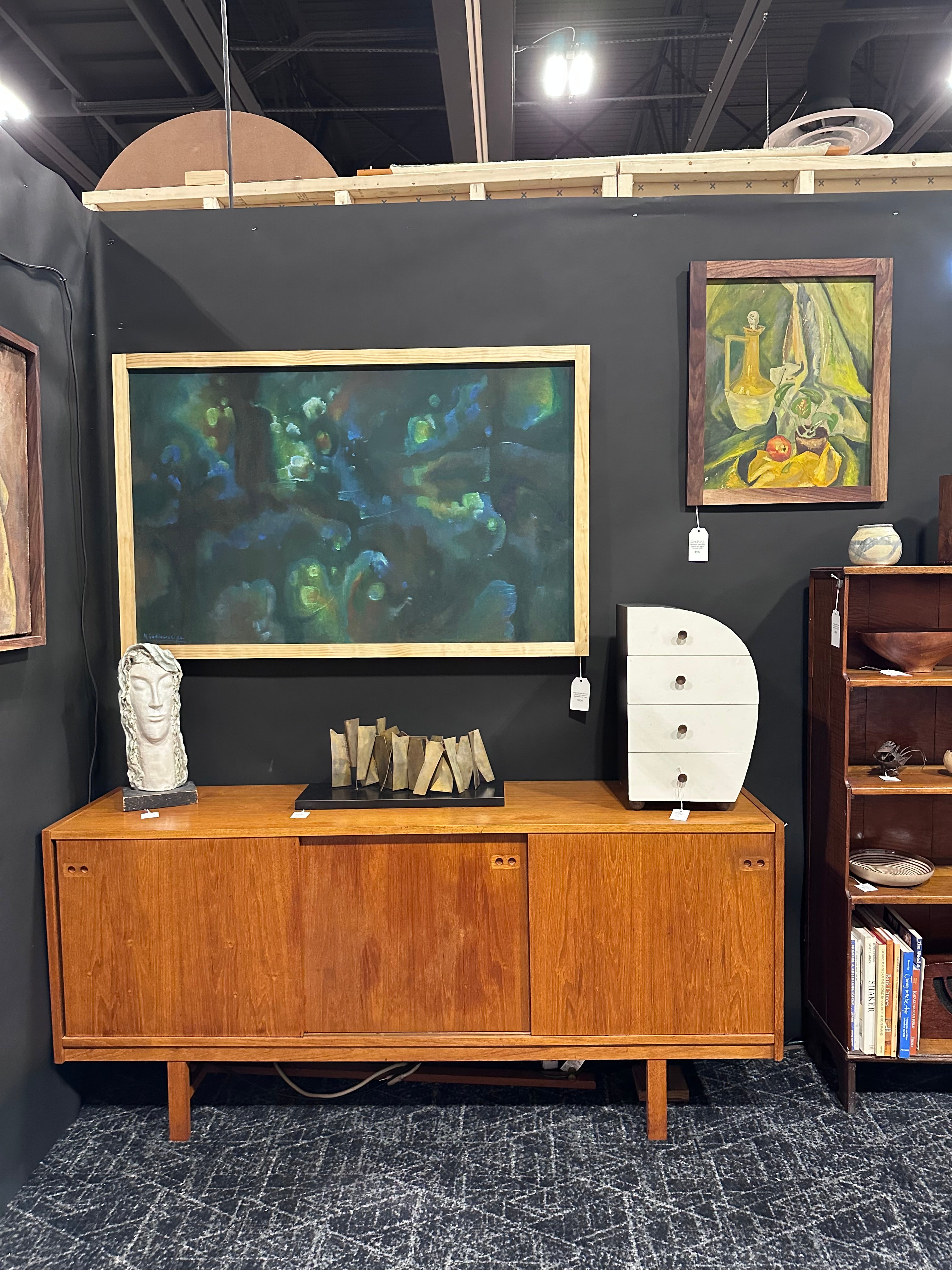 Wooden cabinet with books and a painting on a dark wall