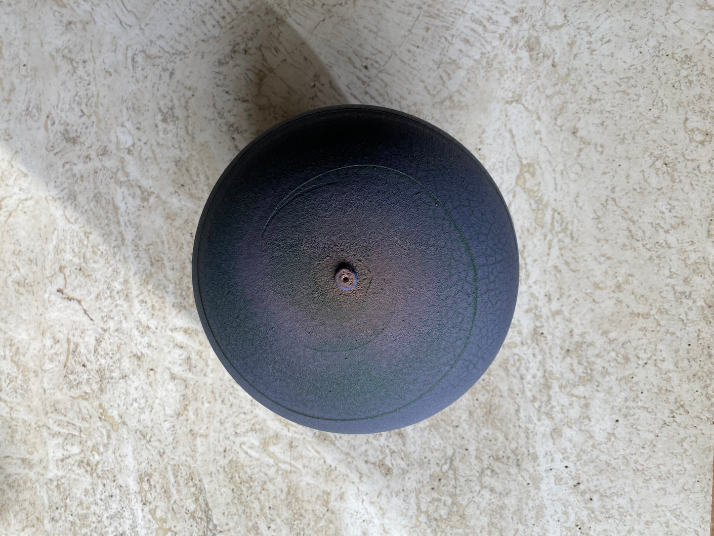 purple ceramic vase on a textured stone surface