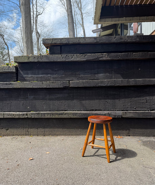 Wooden stool on a concrete surface with steps and trees in the background