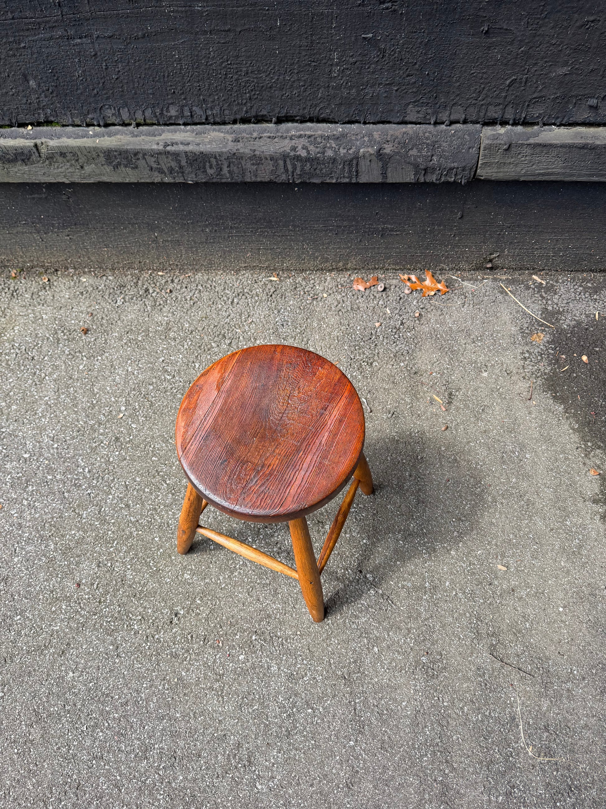 Wooden stool on a concrete floor next to a black wall