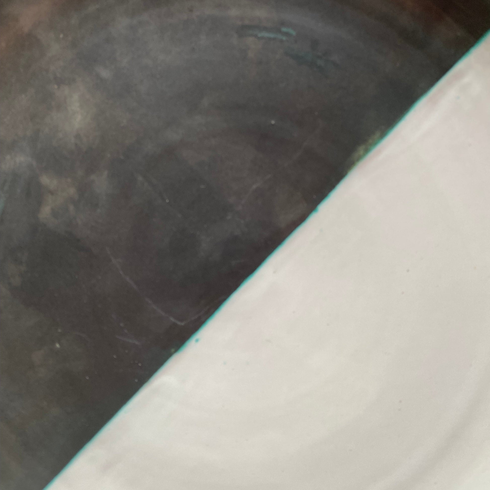 Close-up of a dark metal surface with a white edge