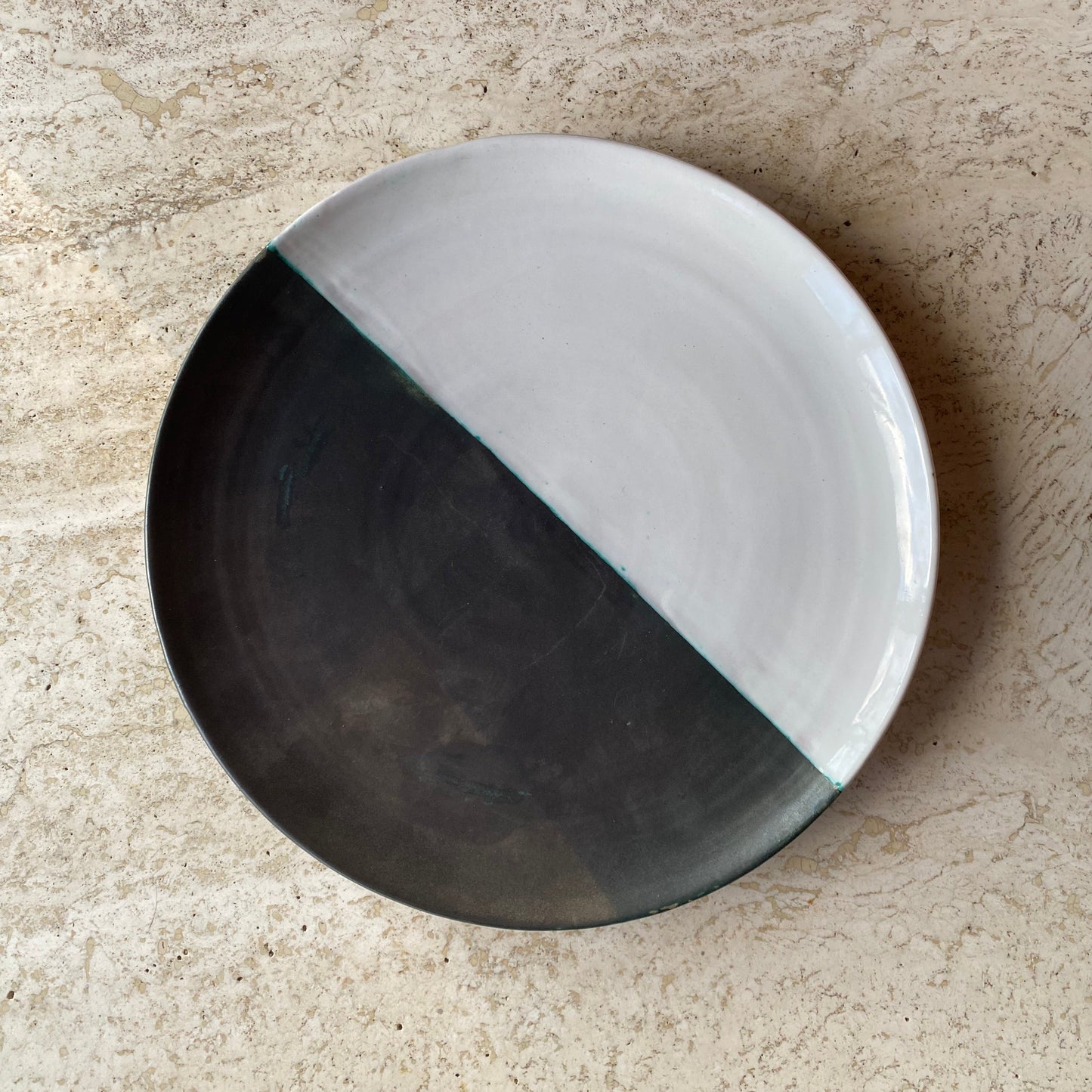 Round ceramic plate with black and white design on a textured surface