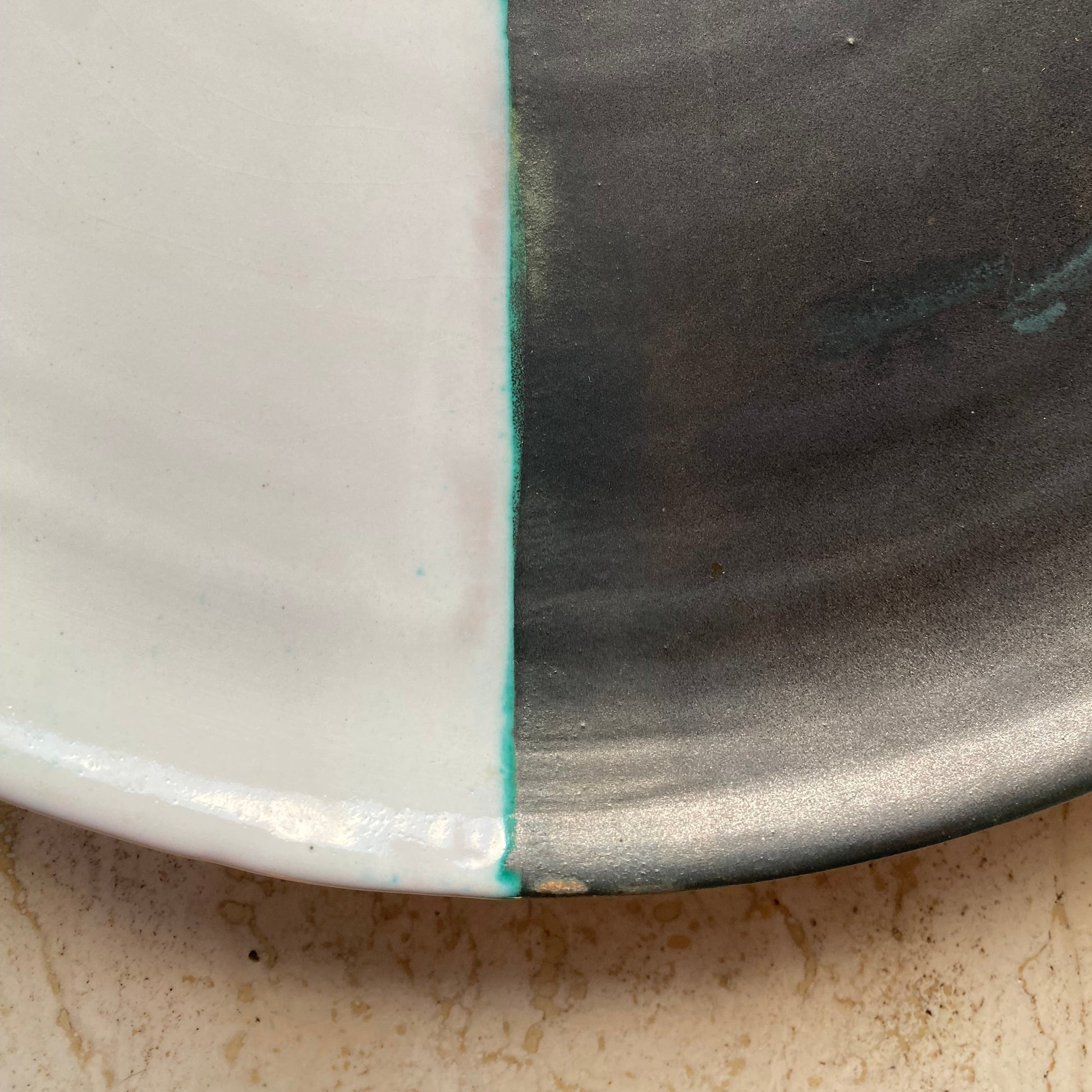 Close-up of a ceramic plate with a glossy finish on a textured surface