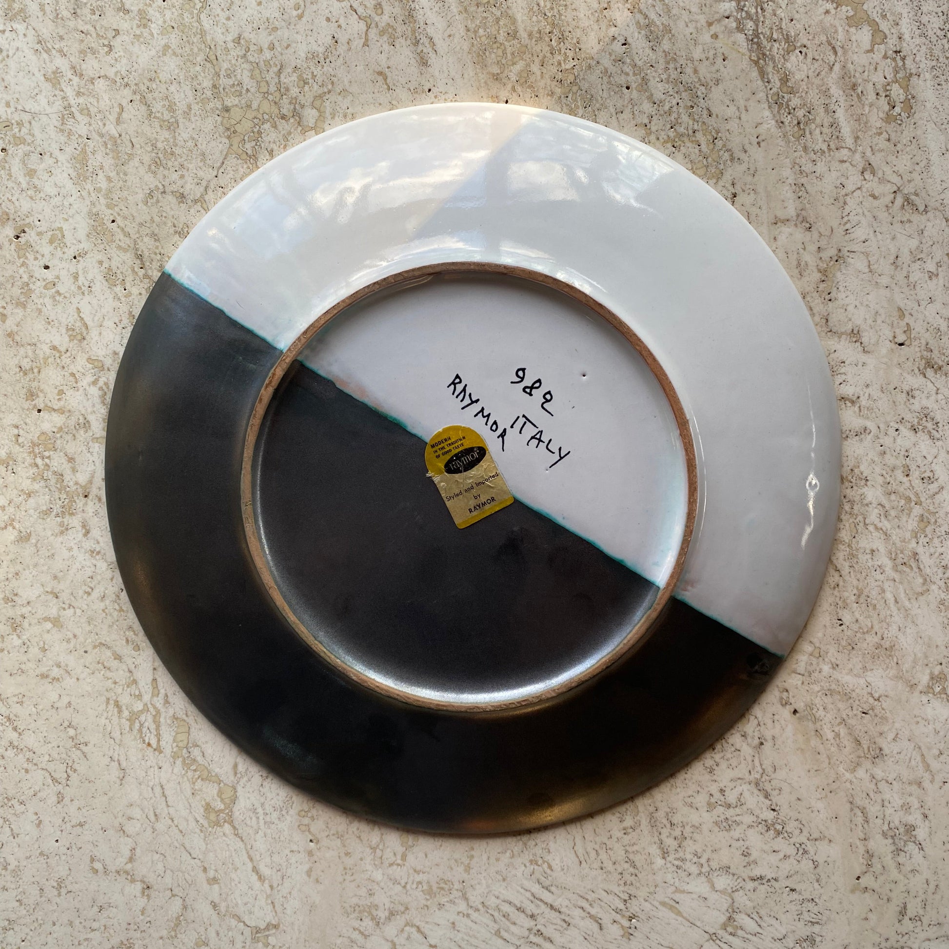 Ceramic plate with a visible brand label on a textured surface