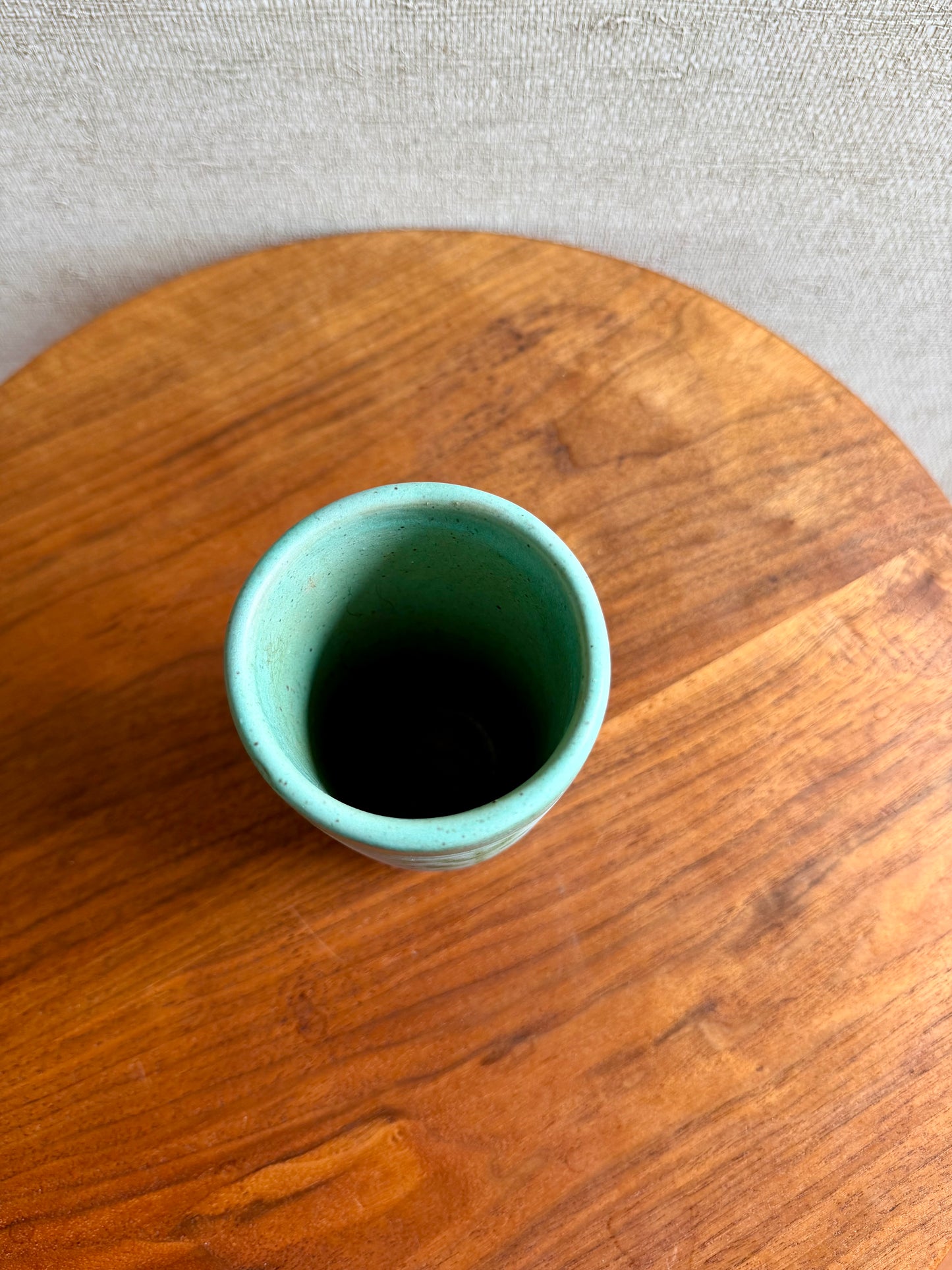 Teal ceramic cup on a wooden surface with a neutral background