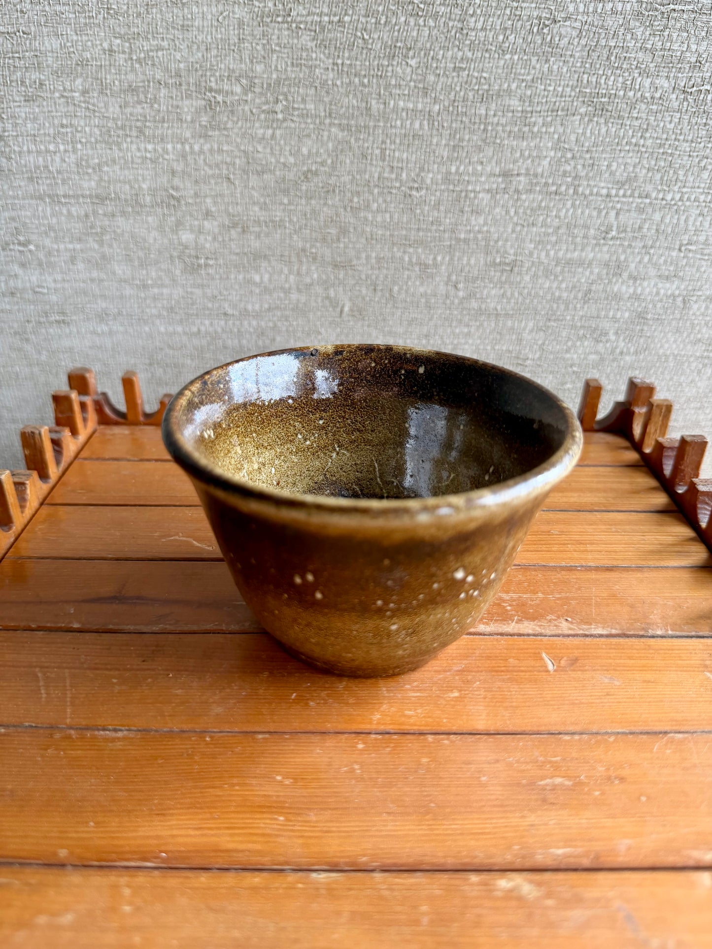Ceramic bowl on a wooden surface with a textured gray wall background