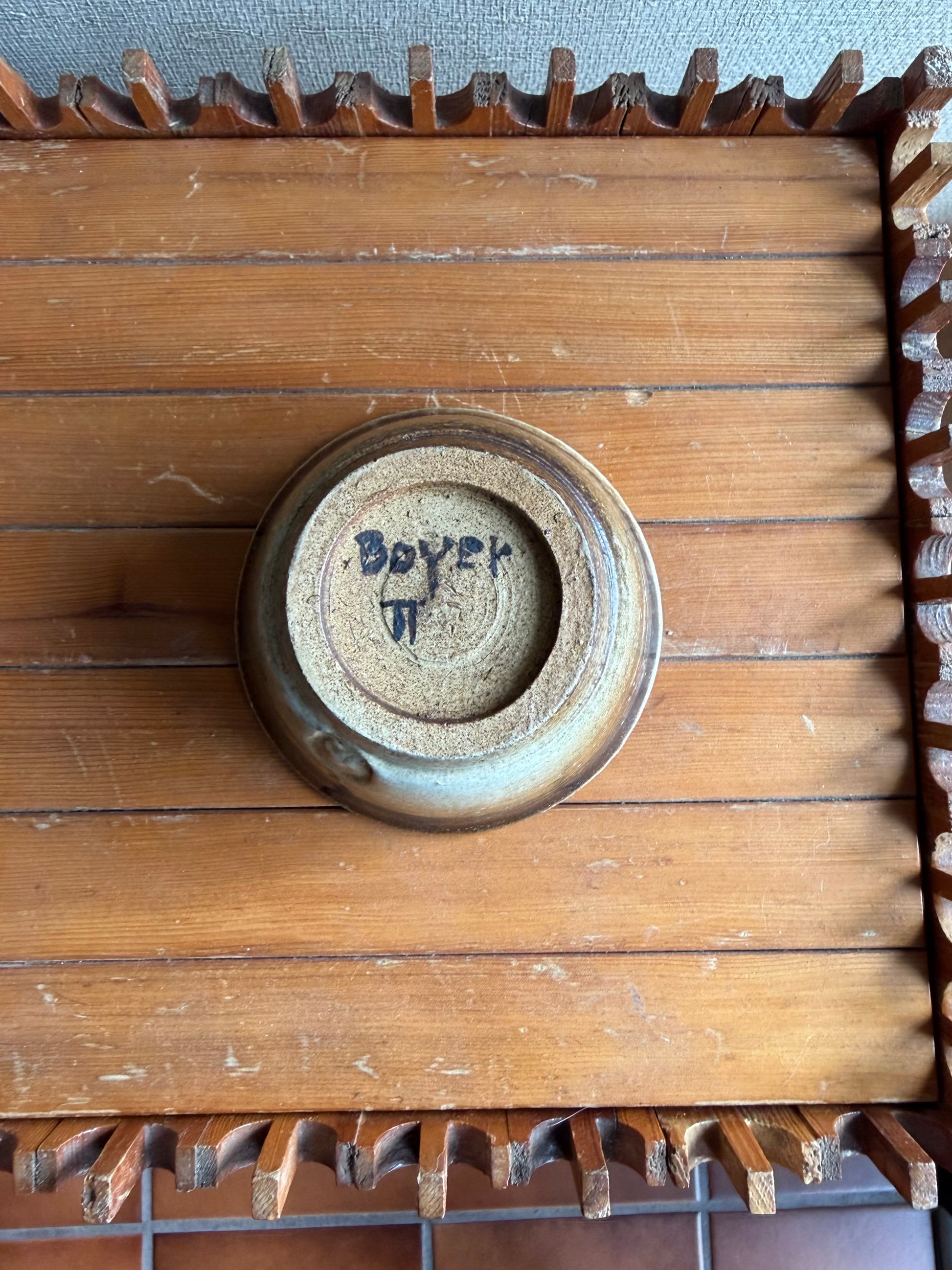 Wooden box with a circular metal component featuring engraved text, on a textured surface.