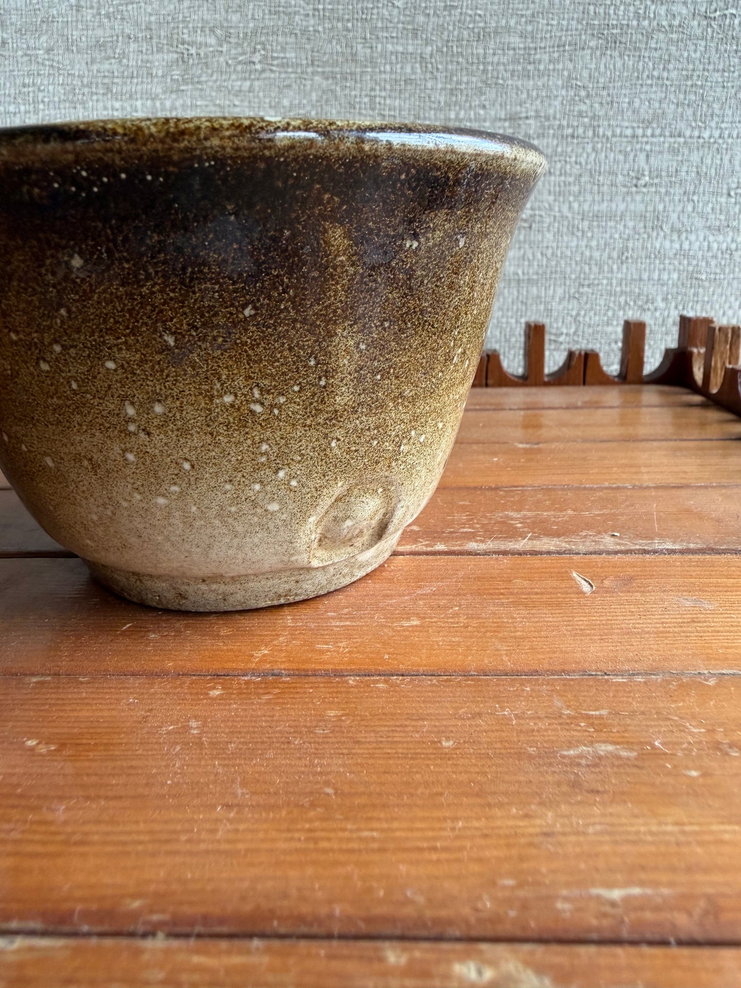 Brown ceramic bowl against a wooden panel background