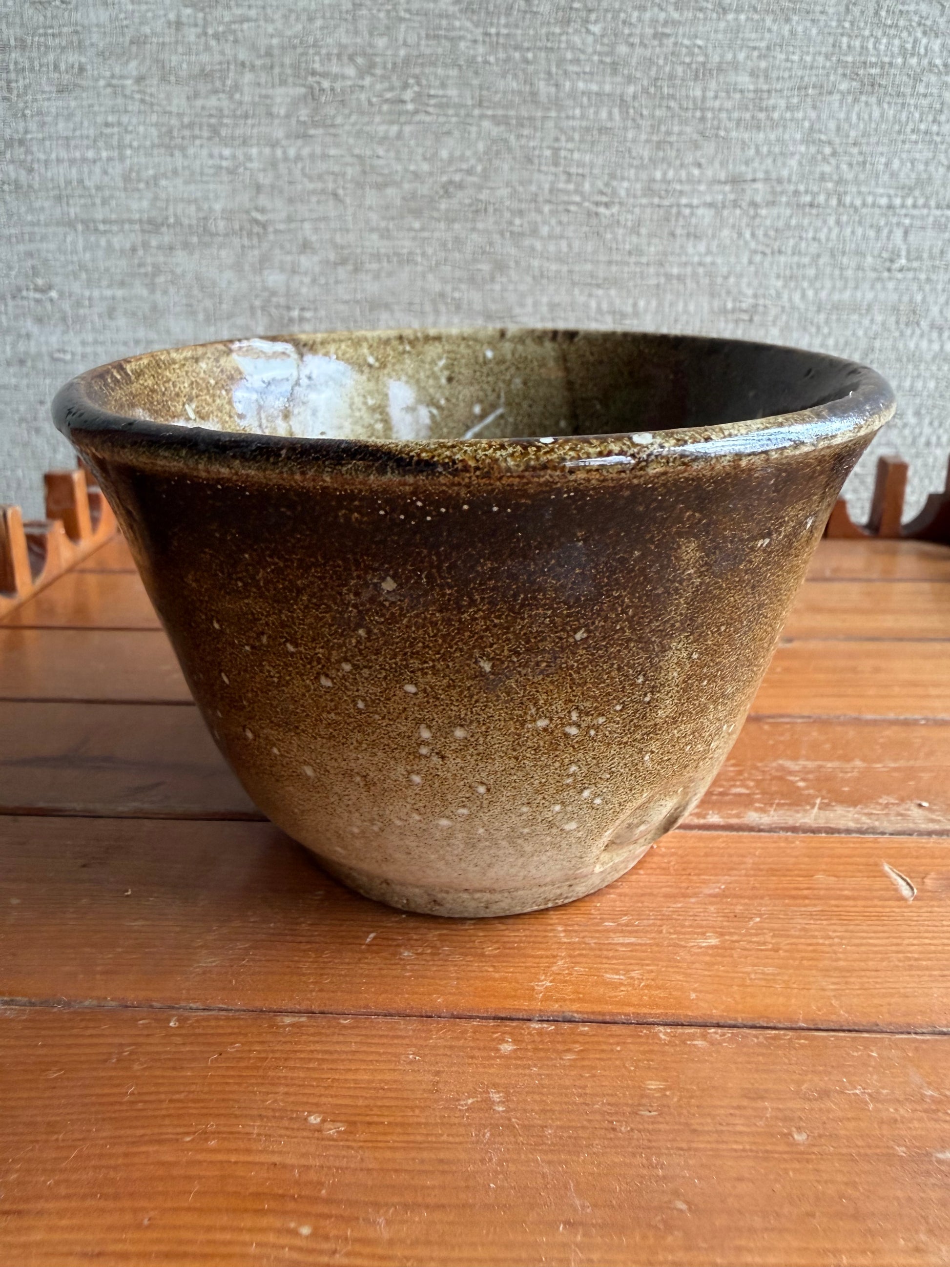 Brown ceramic bowl on a wooden surface with a neutral background