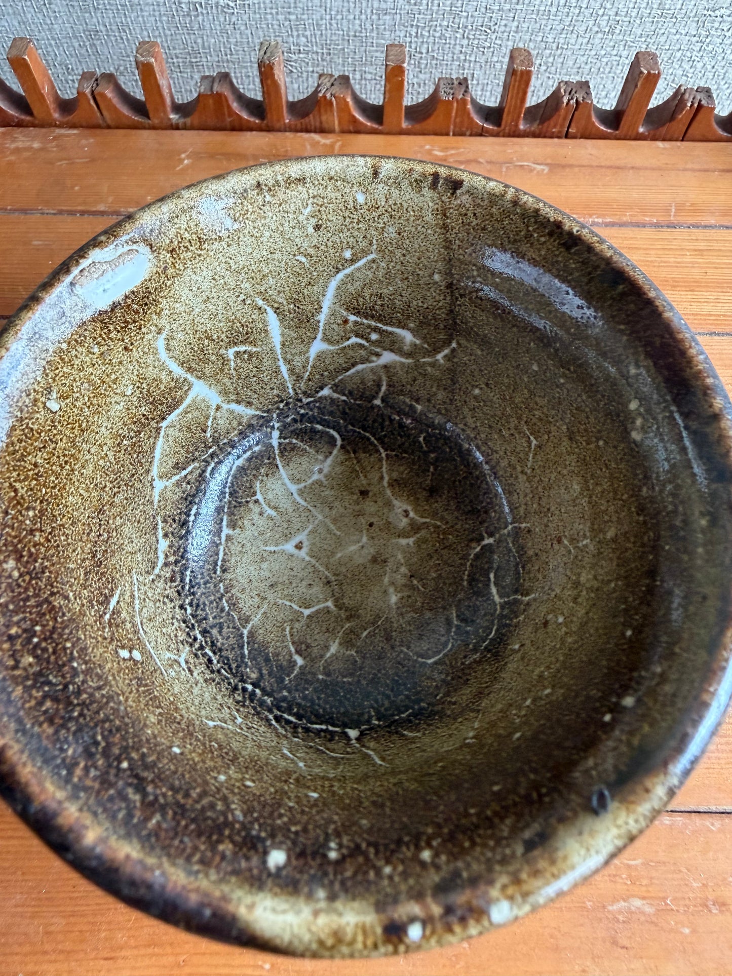 Brown ceramic bowl with a wooden gear on a wooden surface