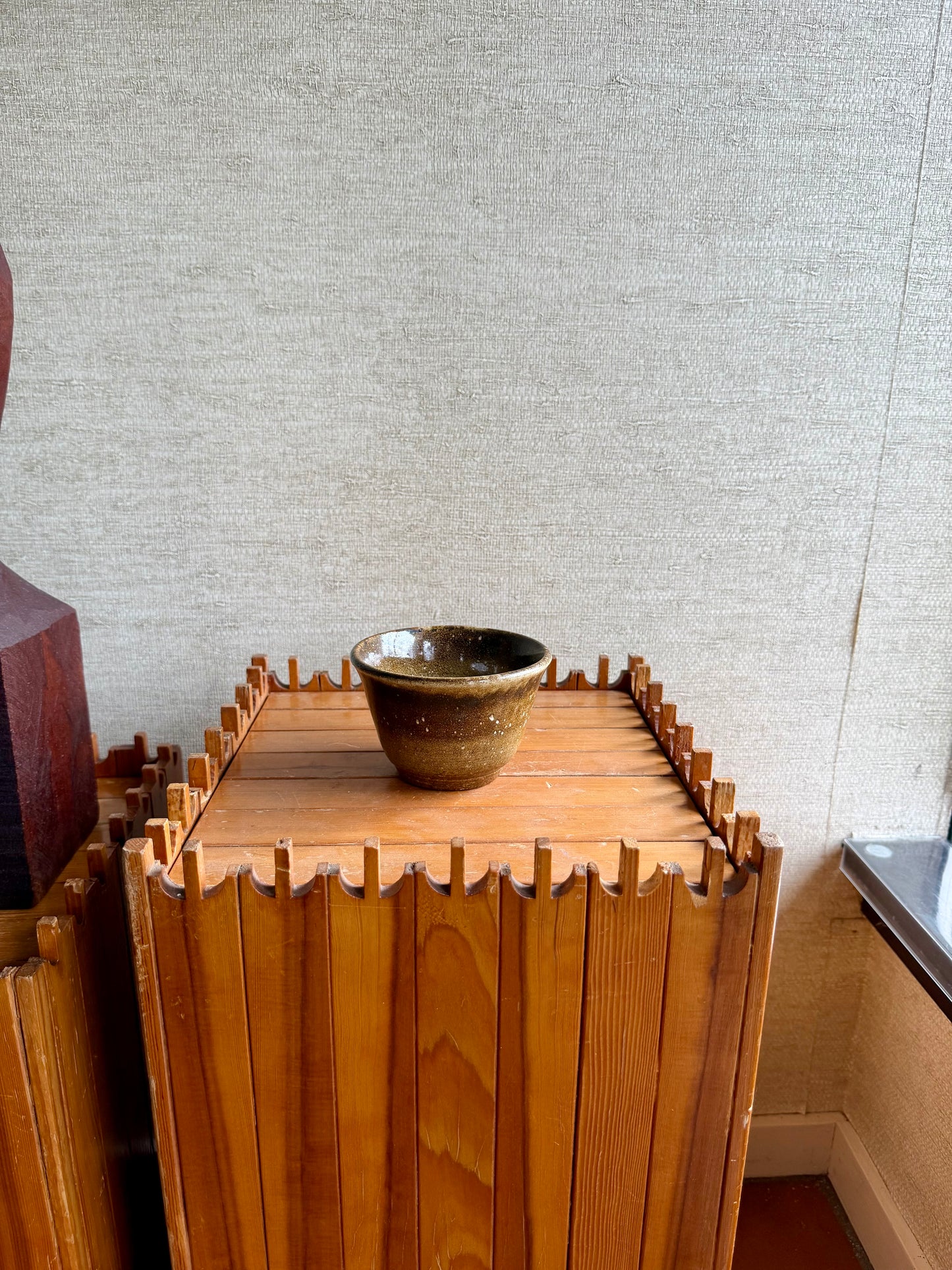 Wooden crate with a ceramic bowl on top against a textured wall.