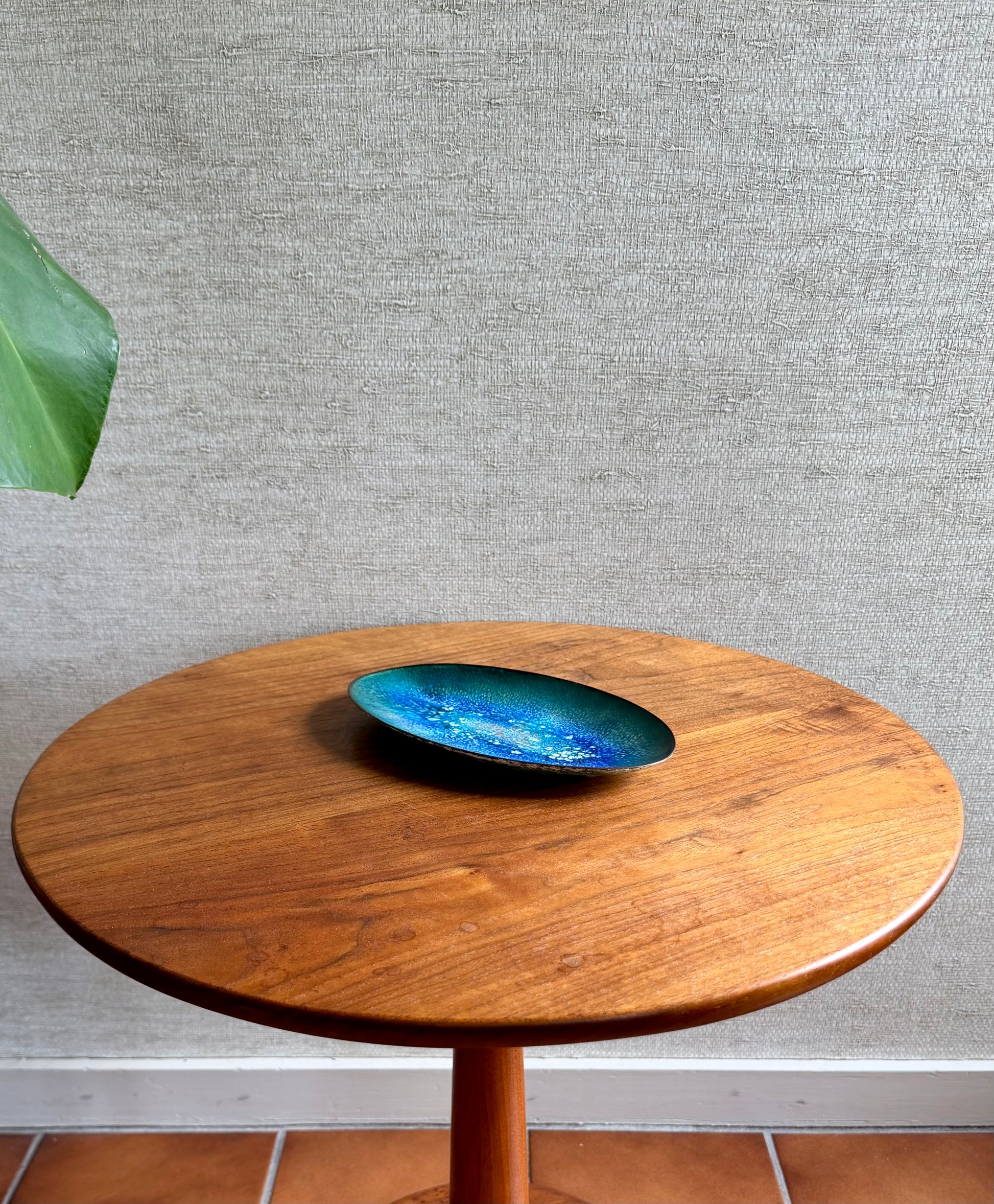 Wooden table with a blue ceramic dish on a gray textured wall background