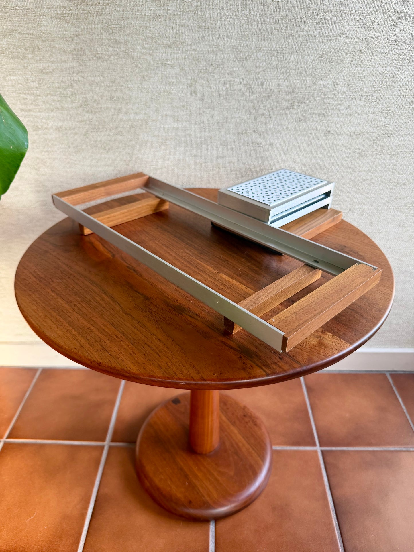 Wooden side table with a metal tray on a tiled floor
