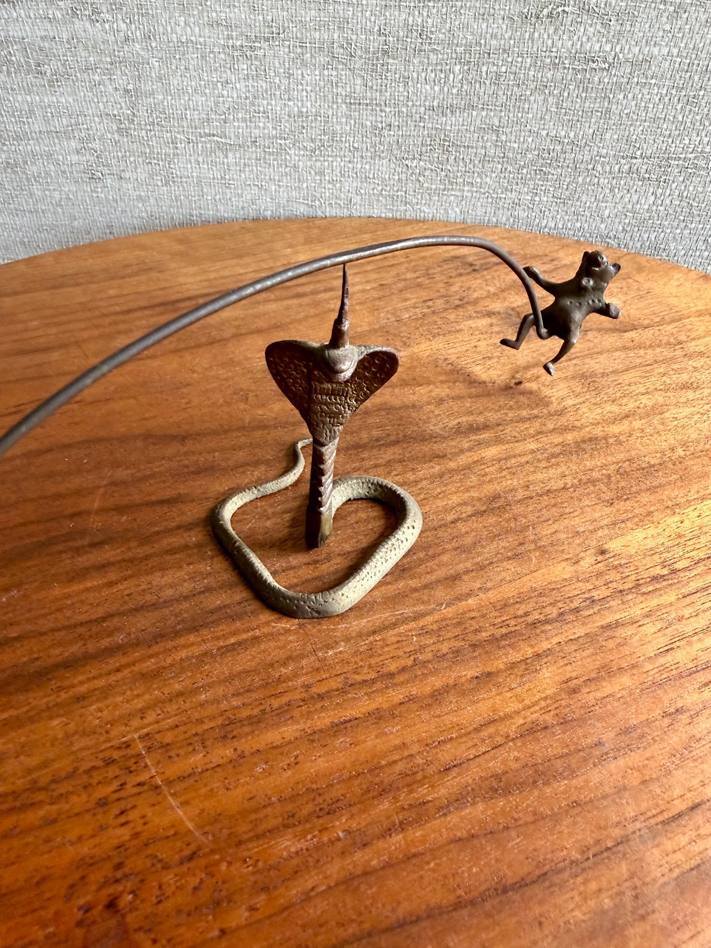 Bronze sculpture of a heart with a snake coiled around it on a wooden surface.