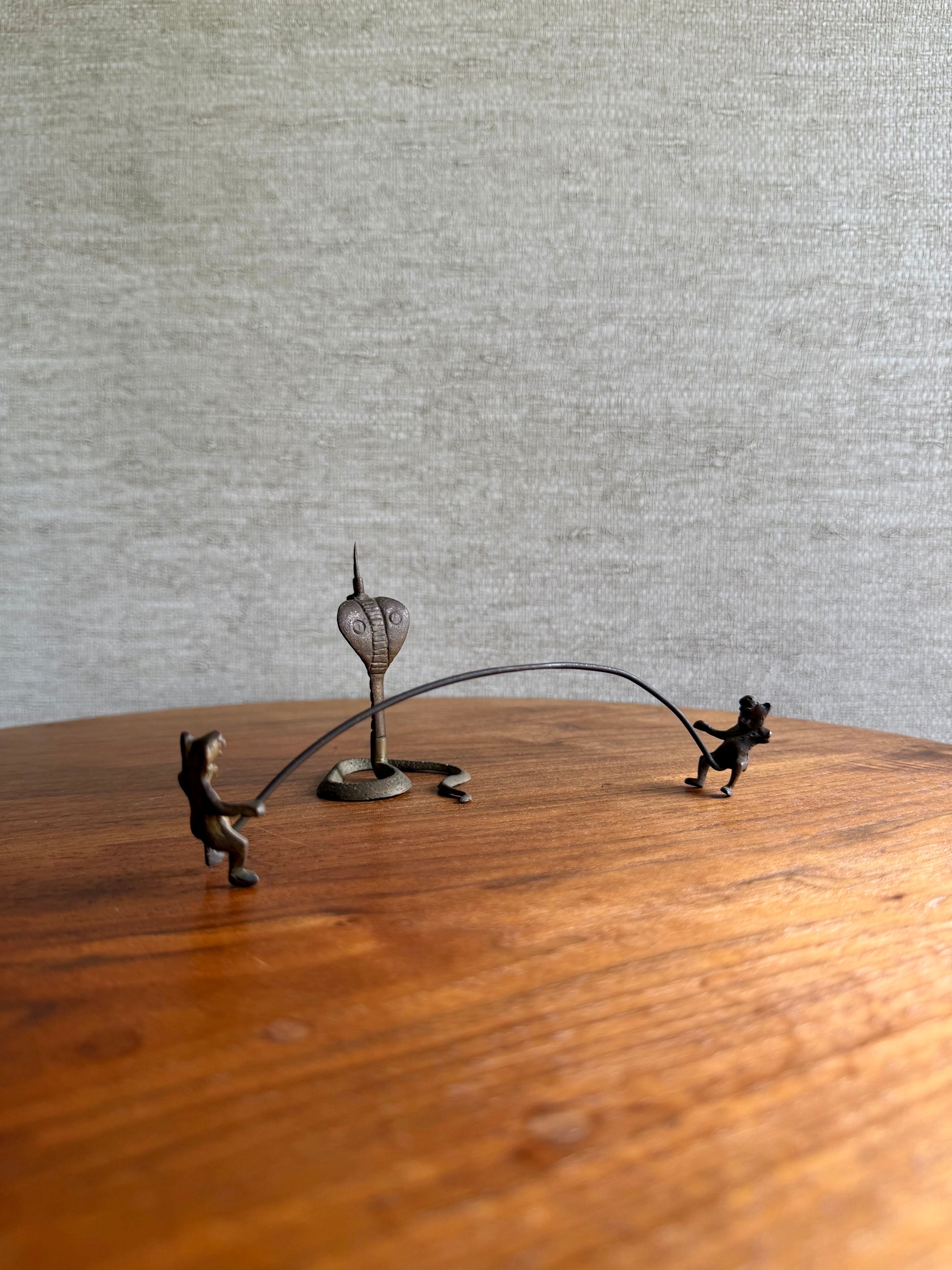 Decorative metal sculpture of two figures with a heart on a wooden surface.