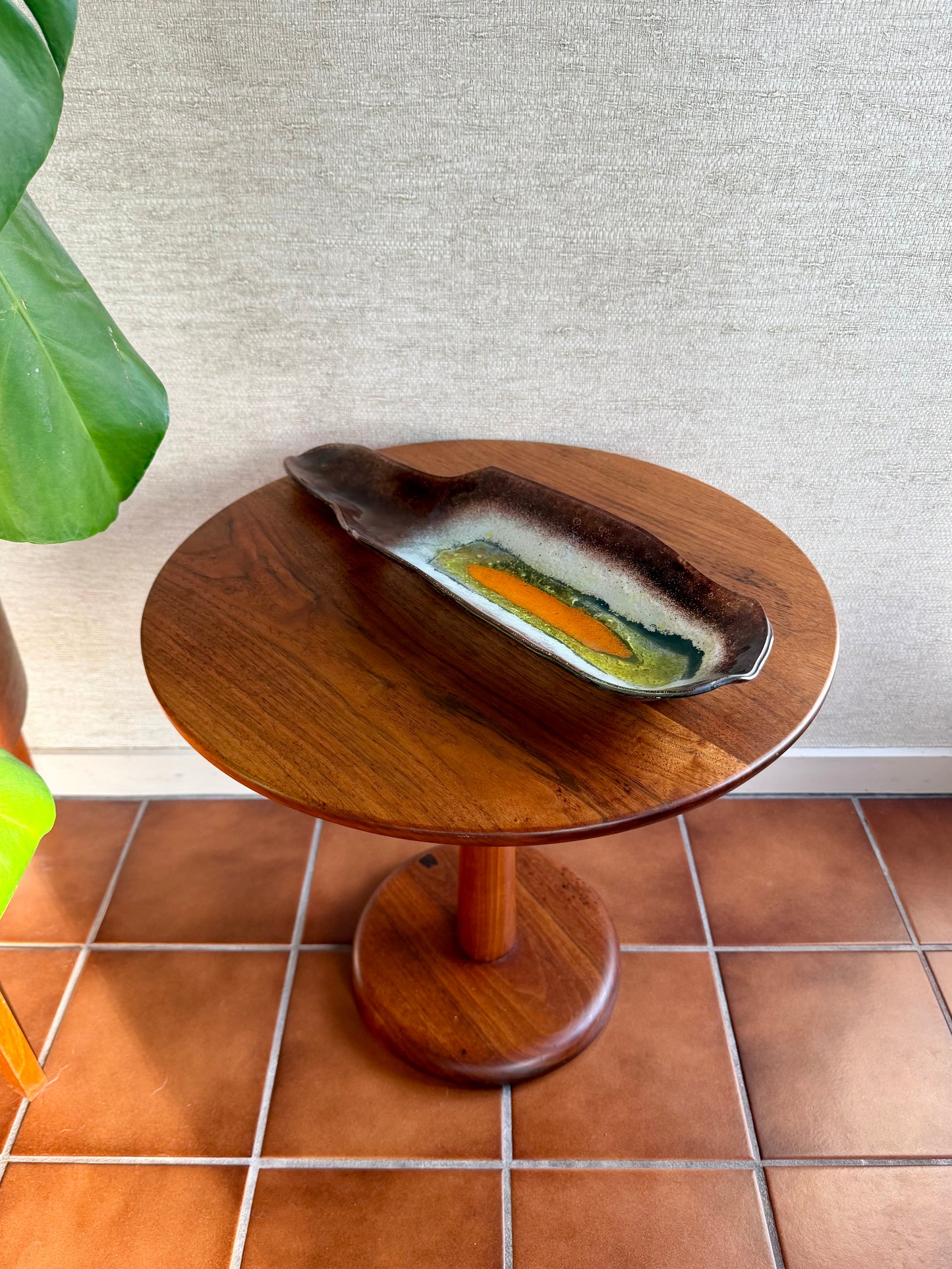 Wooden side table with a decorative item on a tiled floor