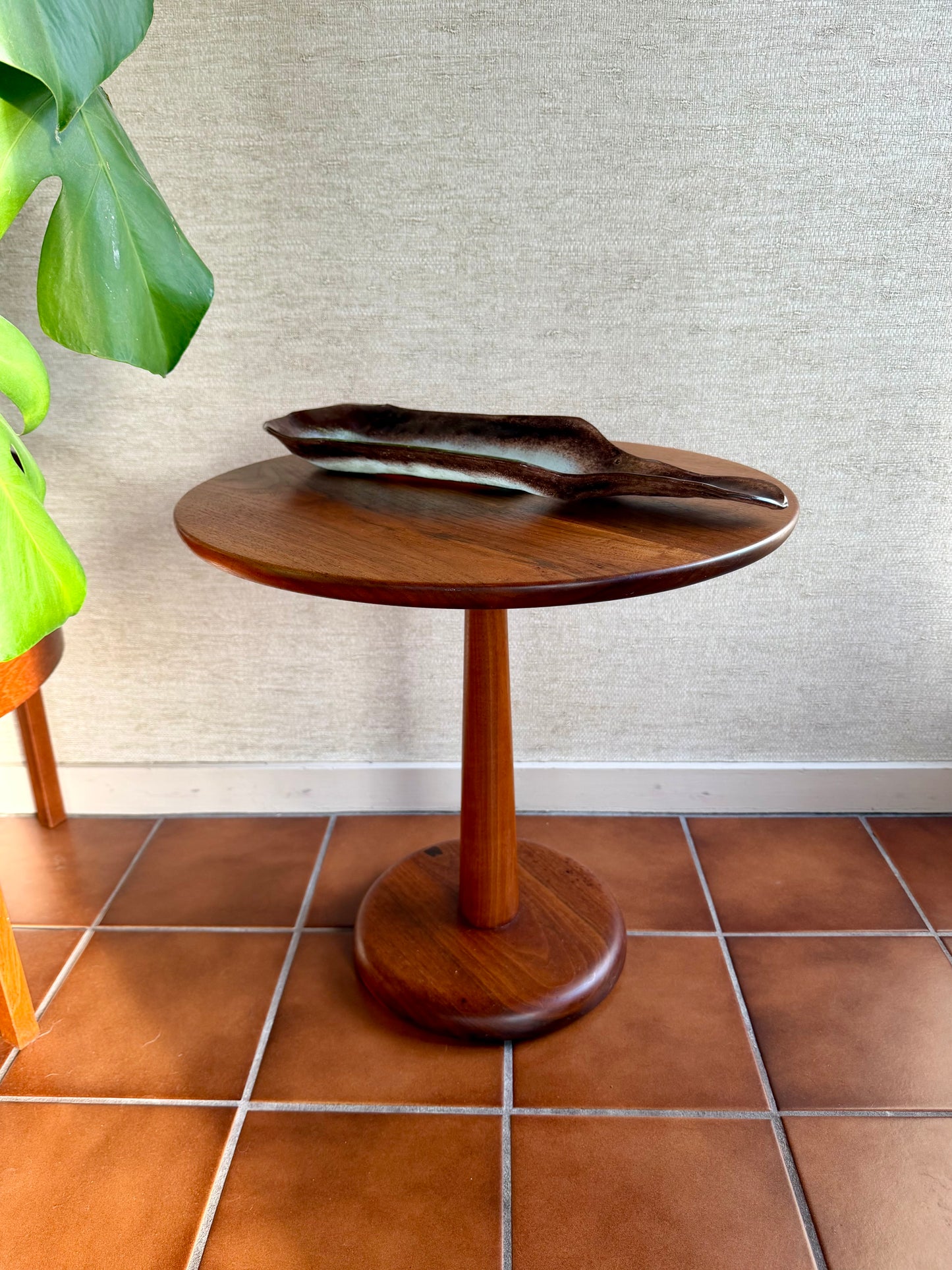 Wooden side table with a plant on a tiled floor