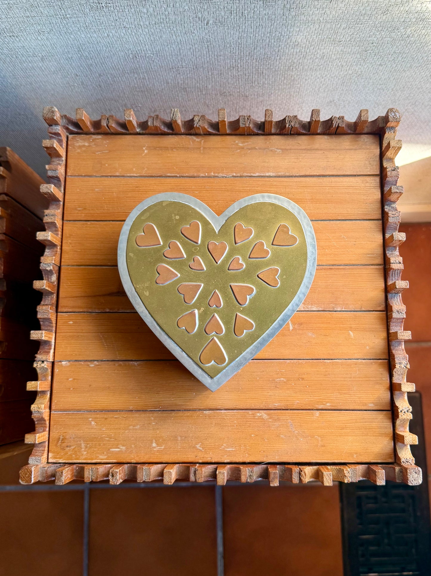 metal box with a decorative heart on top against a neutral background