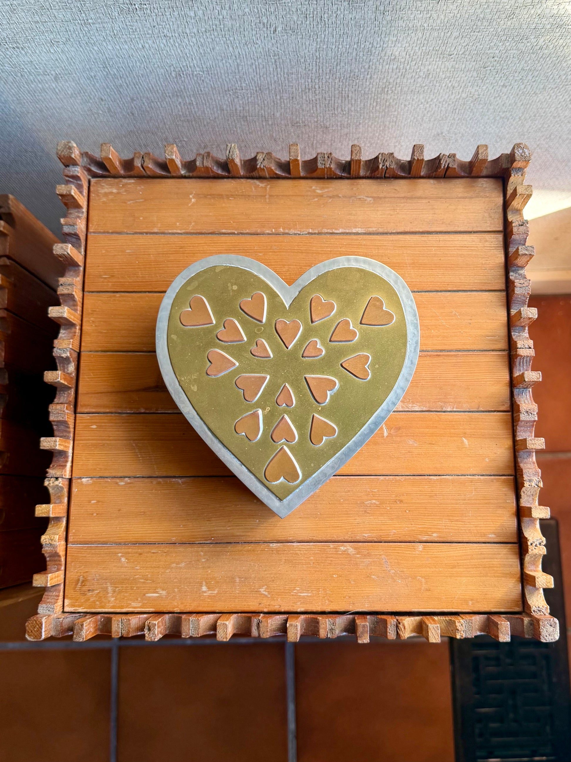 metal box with a decorative heart on top against a neutral background