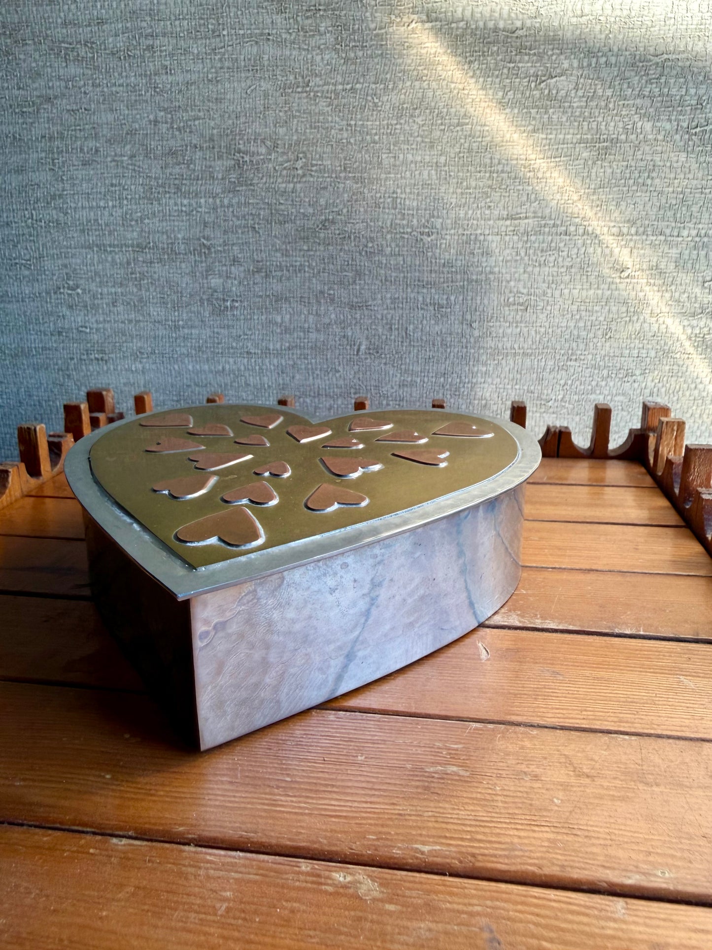 Metal heart-shaped box on a wooden surface with a textured gray background
