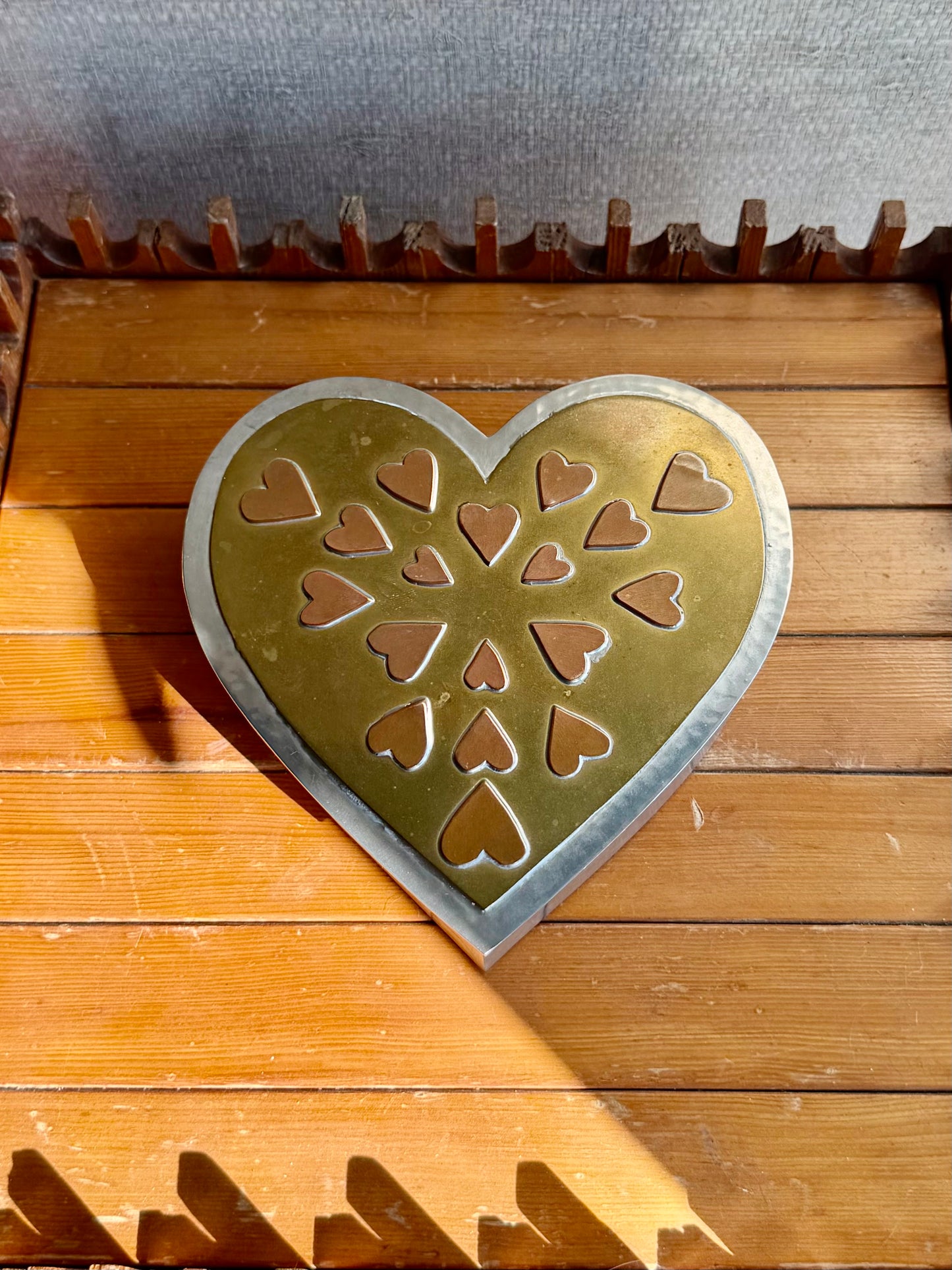 Heart-shaped metal stamp with cut-out heart patterns on a wooden surface