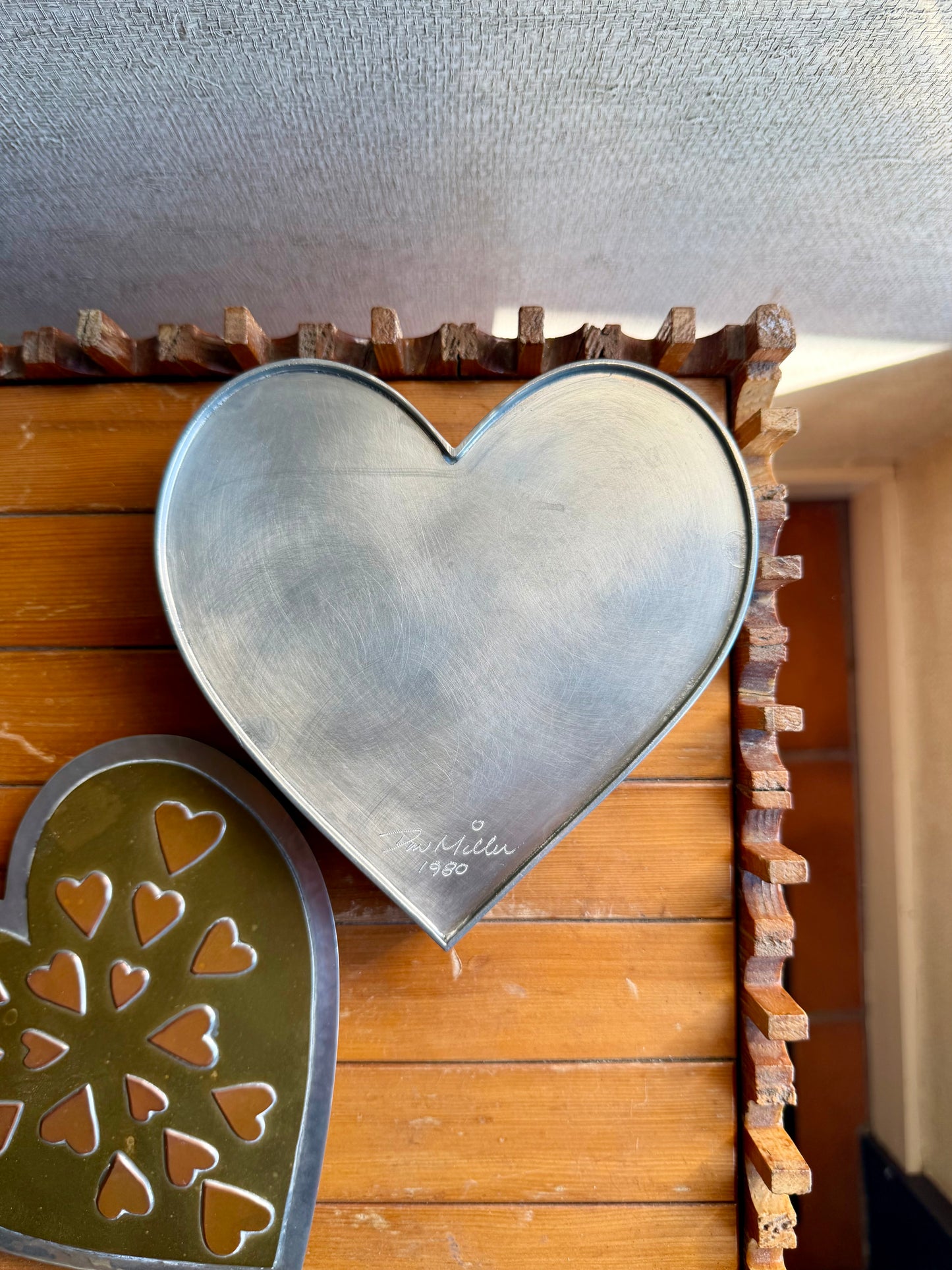 Heart-shaped metal cookie cutters on a wooden surface with a textured wall background.