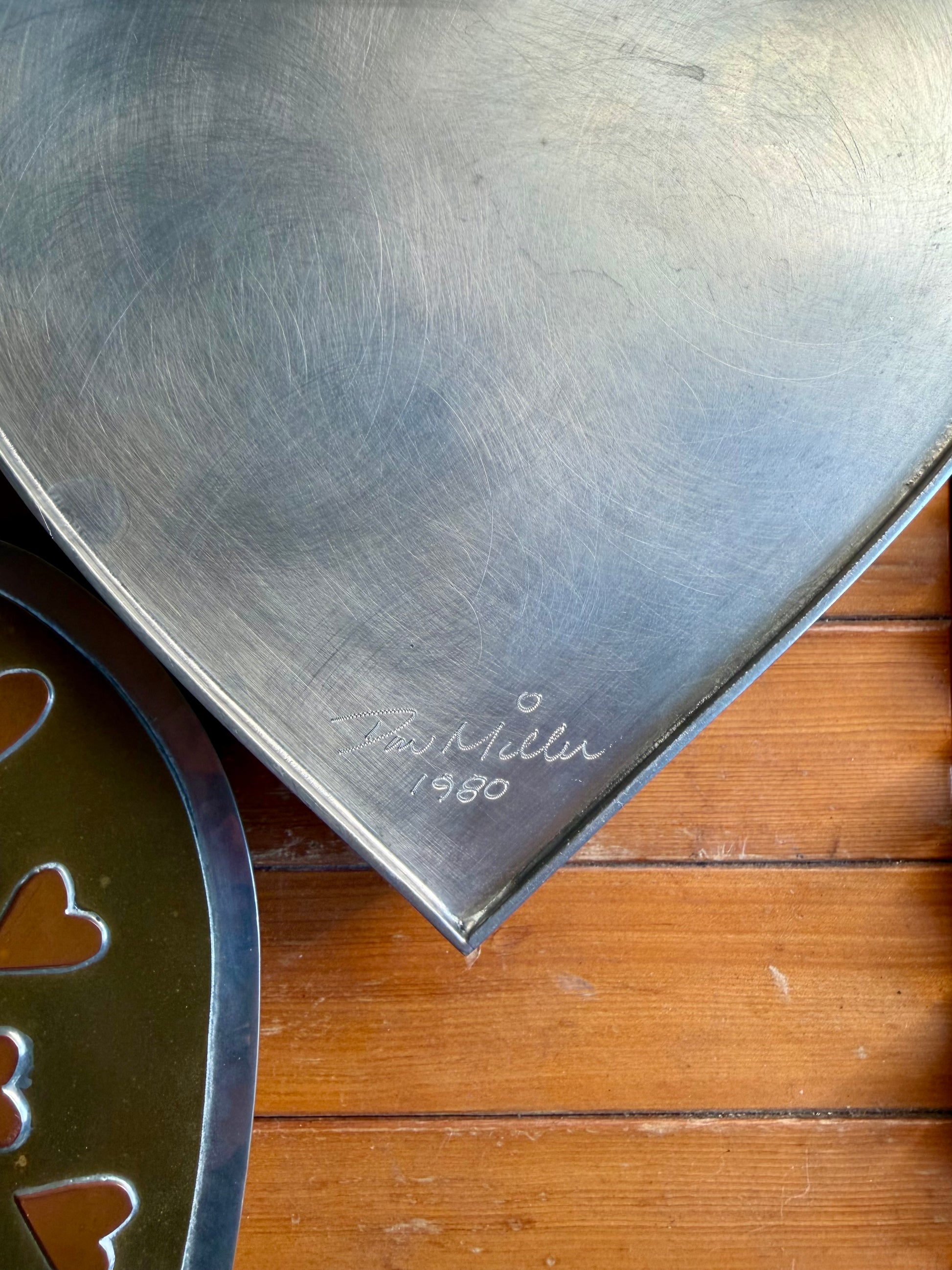 Metal object with 'Bob Miller' signature and year on a wooden surface