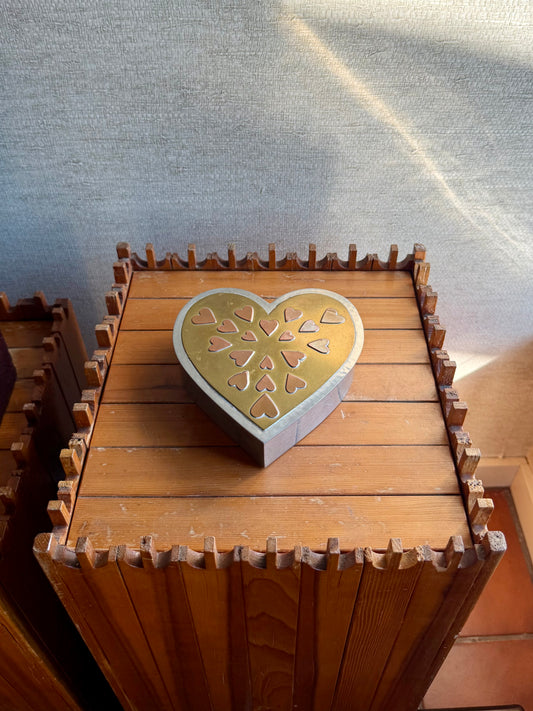 Wooden box with a heart-shaped lid featuring cut-out patterns on a textured surface.