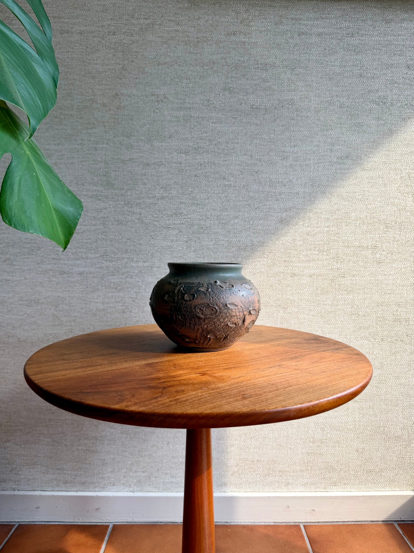 Wooden table with a ceramic vase on a textured wall background
