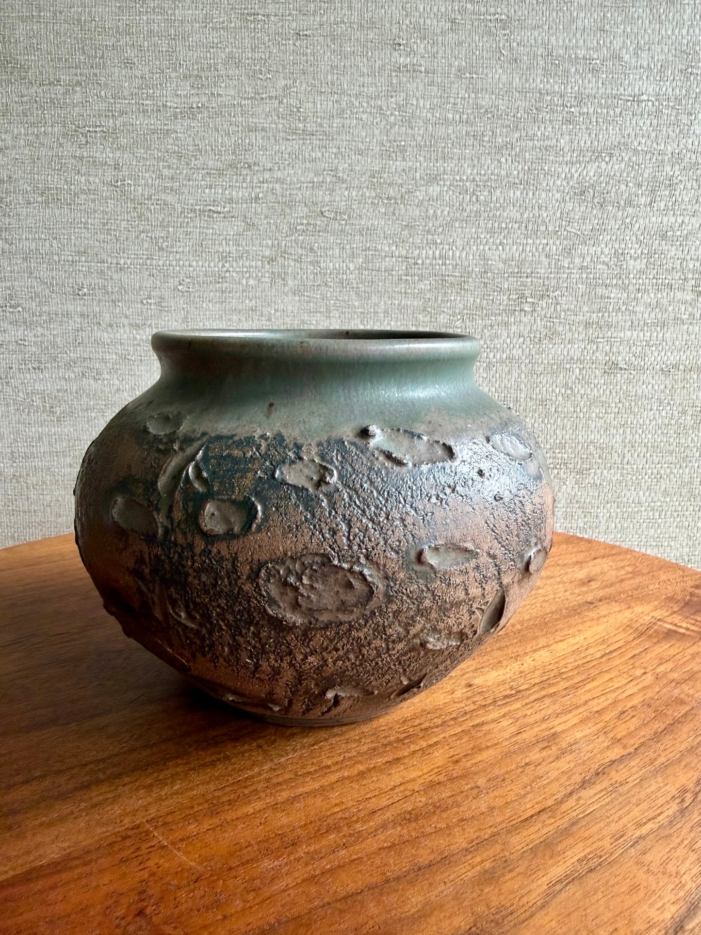Ceramic vase with textured surface on a wooden surface