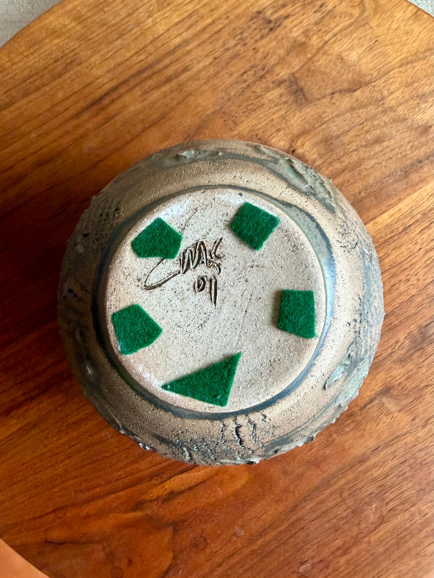 Bottom of a ceramic pottery pot on a wooden surface