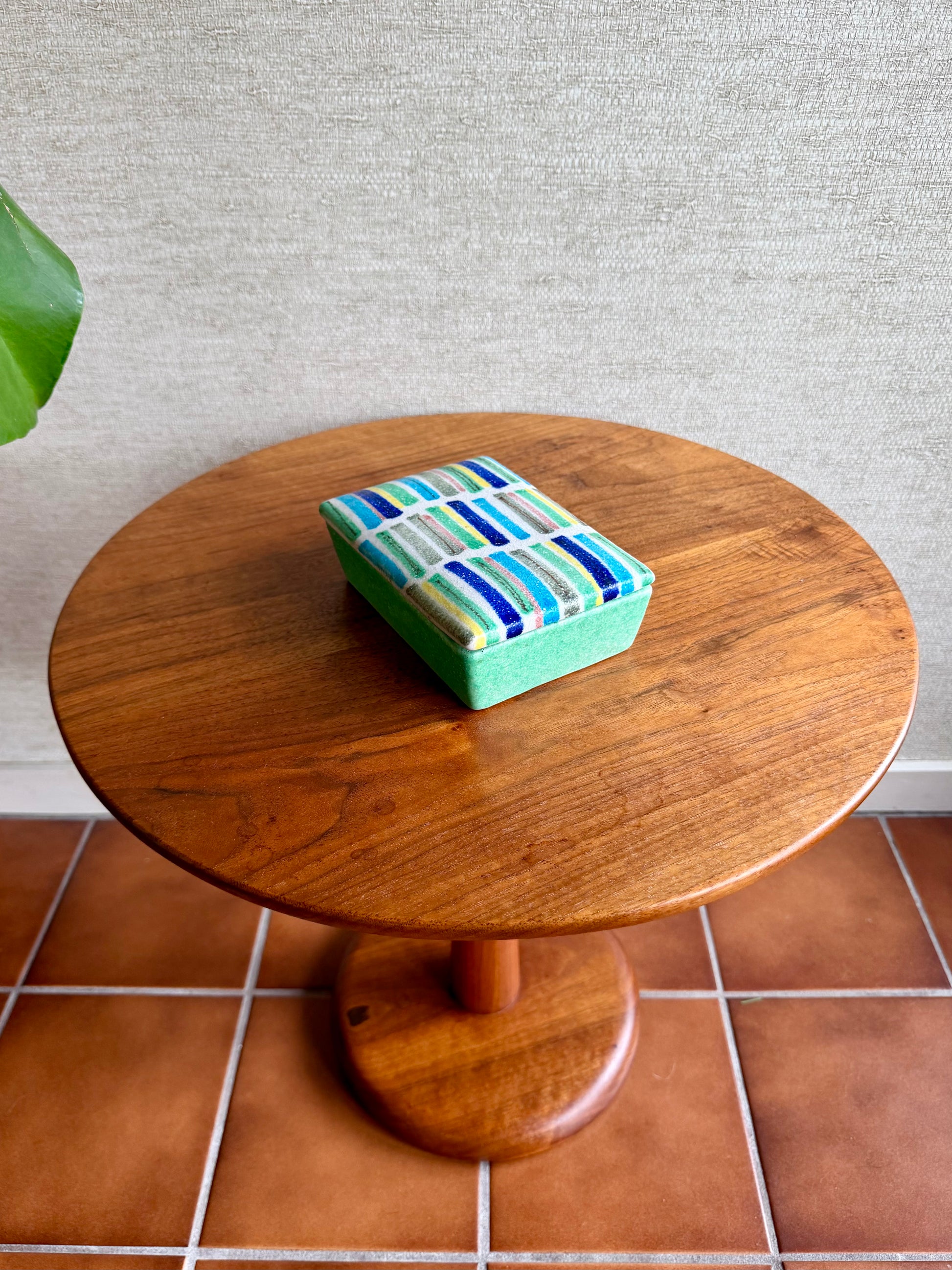 Wooden table with a green box on a tiled floor