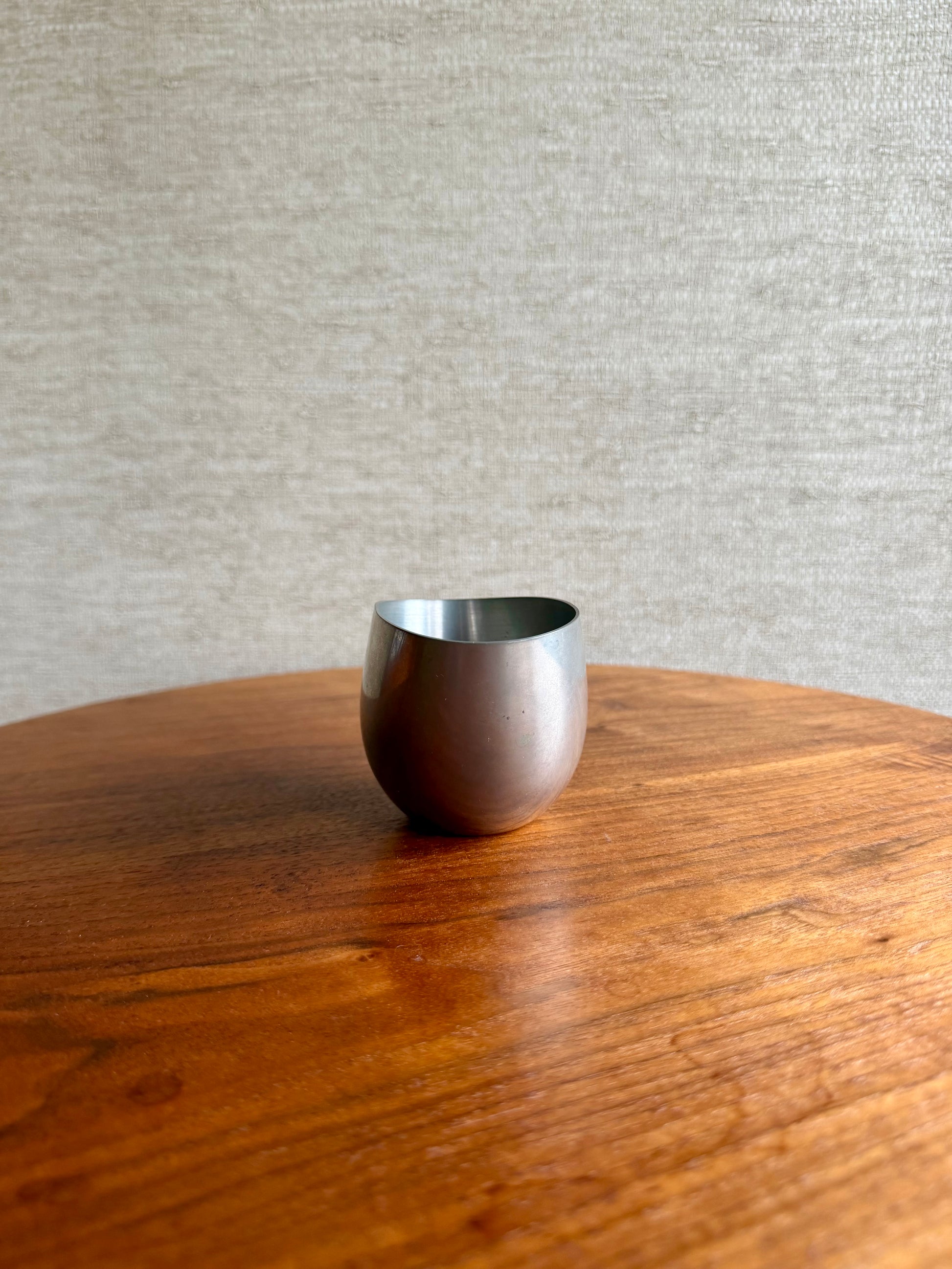 Silver cup on a wooden table with a gray textured wall background
