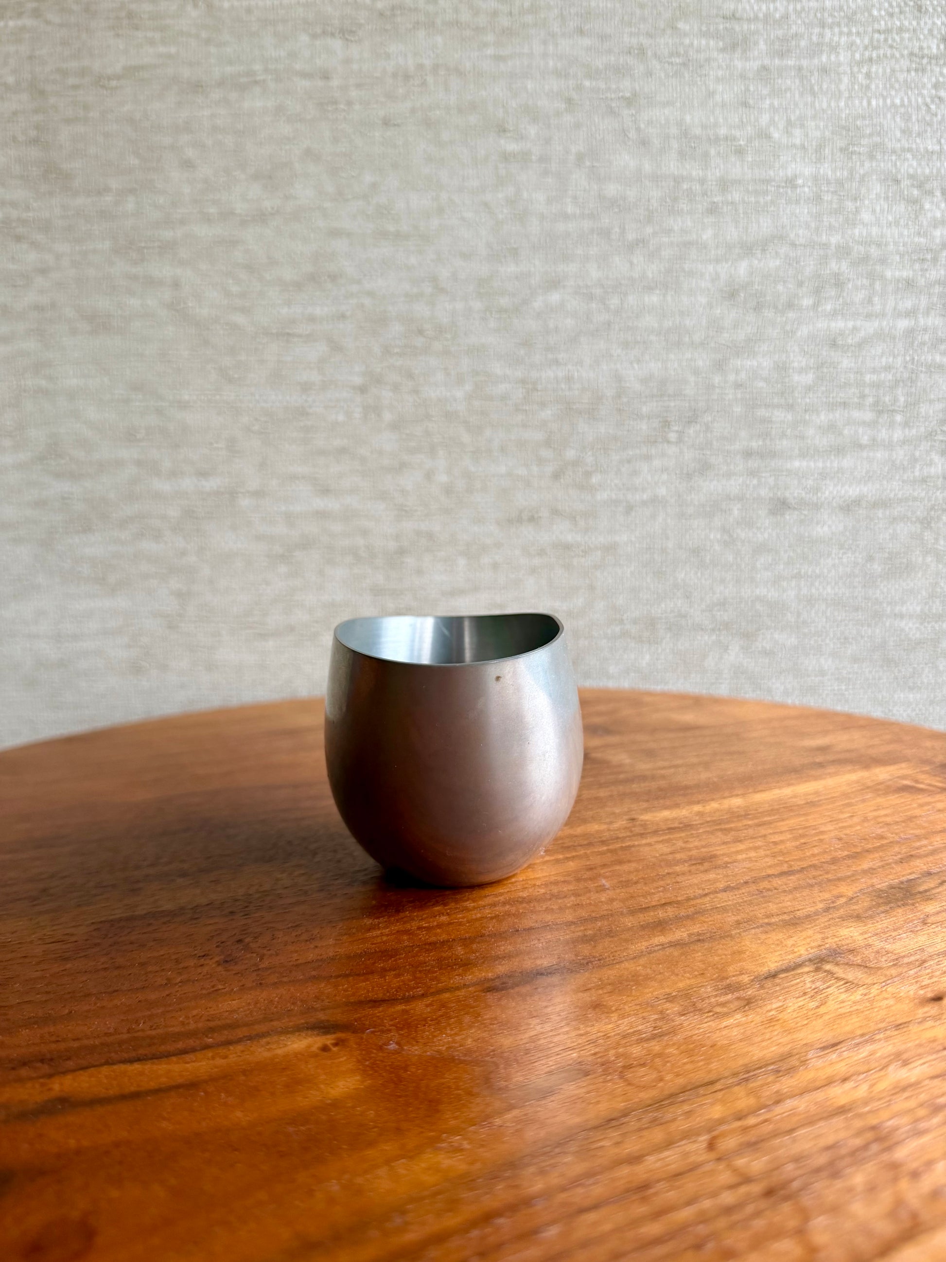 Metal cup on a wooden surface with a neutral background